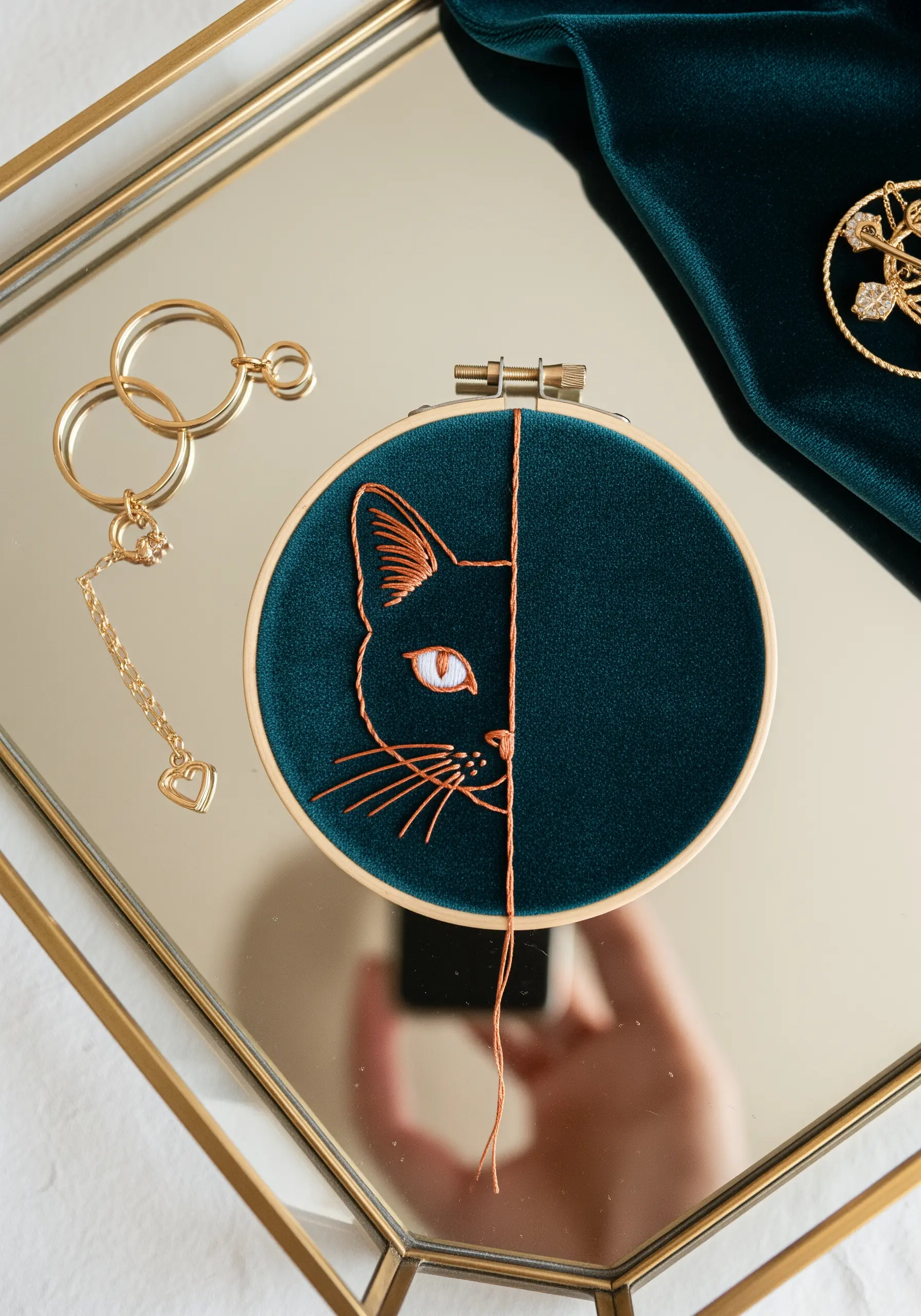 Embroidery of a cat's half-face with one side in copper metallic thread and a bead for an eye.