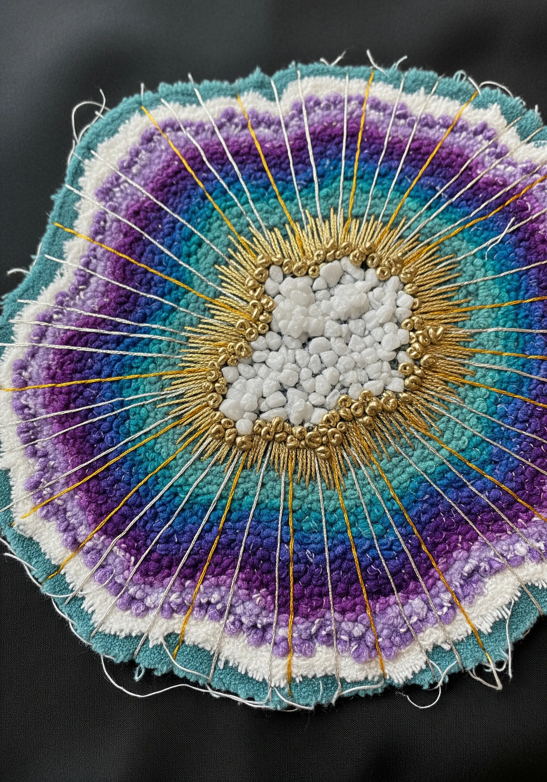 Mixed-media embroidery of a geode using beads, metallic thread, and punch needle loops.