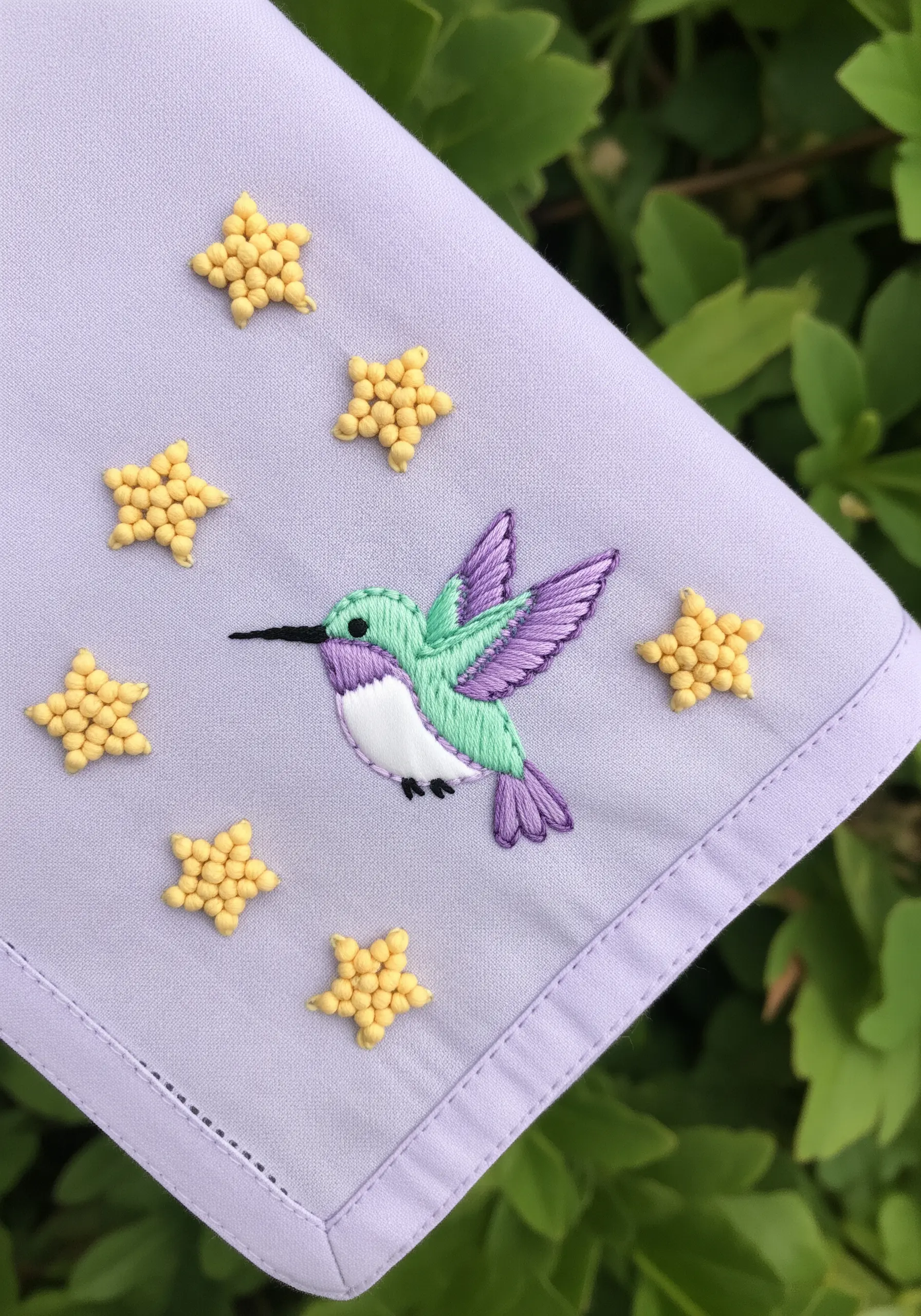 Pastel hummingbird with beaded yellow stars on a lavender handkerchief.