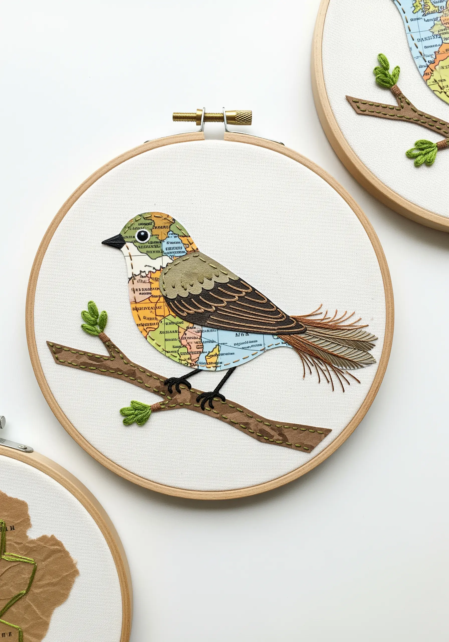 A bird made from map paper collaged onto fabric, with embroidered feather details.