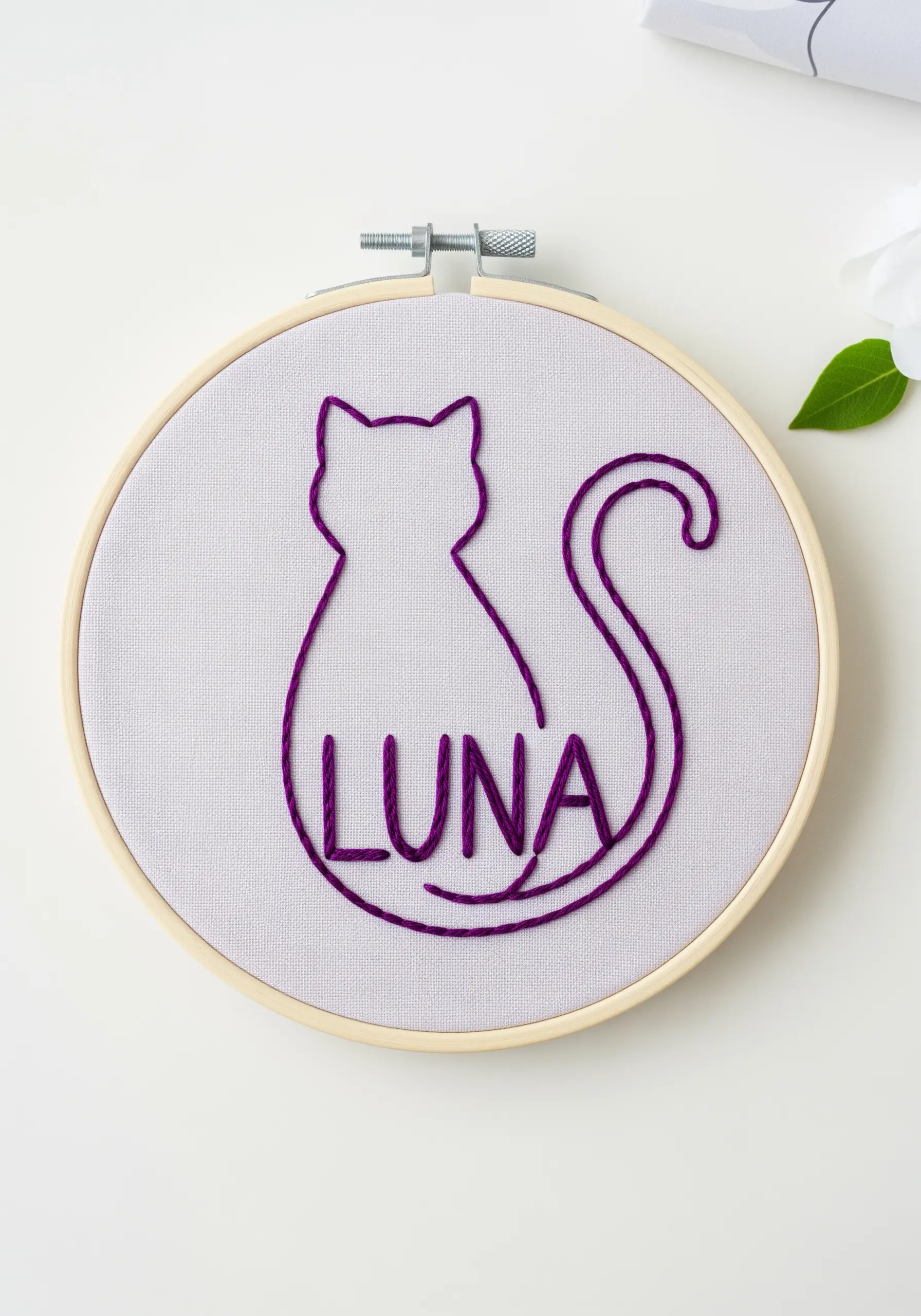 A cat silhouette in purple thread with the name 'Luna' integrated into the design.
