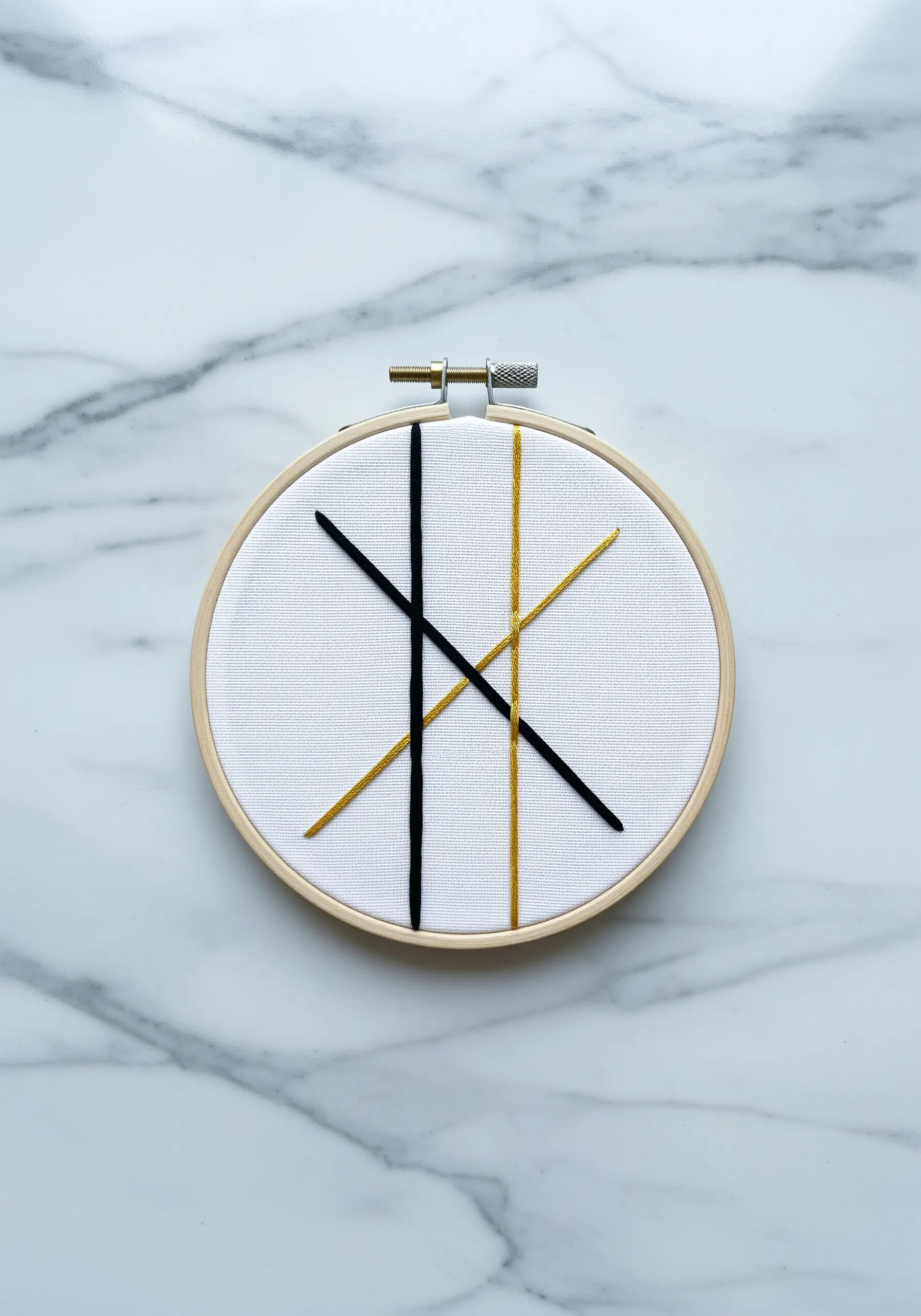Abstract modern art with intersecting black and gold lines on white fabric.