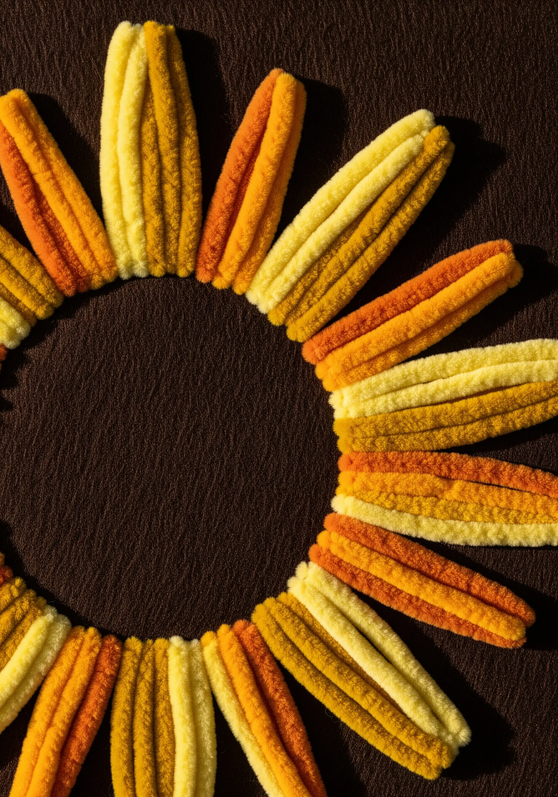 Close-up of a sun motif made with thick, fuzzy chenille yarn in yellow and orange