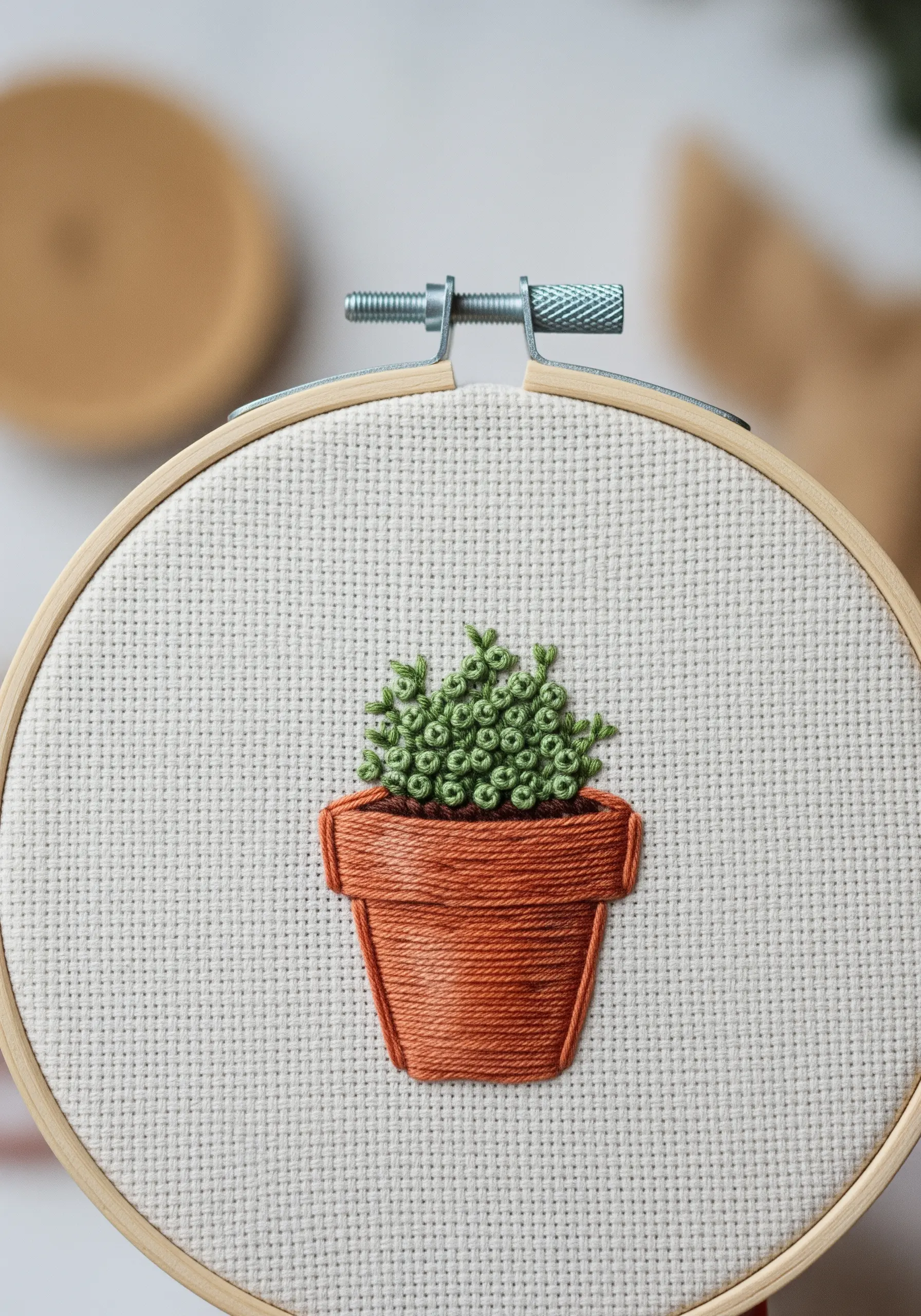 A small potted plant with a satin-stitched pot and French knot leaves.