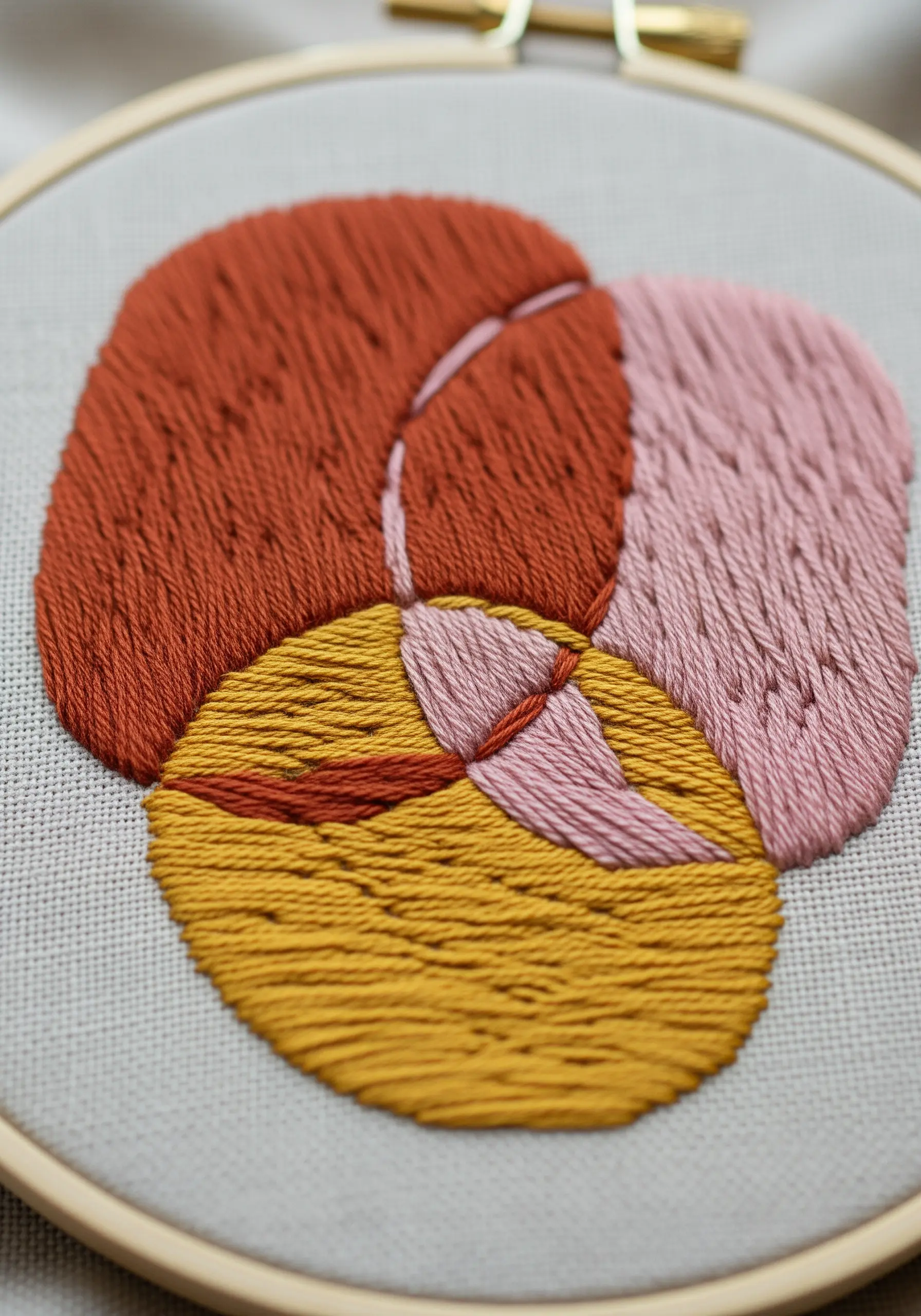 Abstract embroidery of overlapping shapes filled with dense, textured stitches.