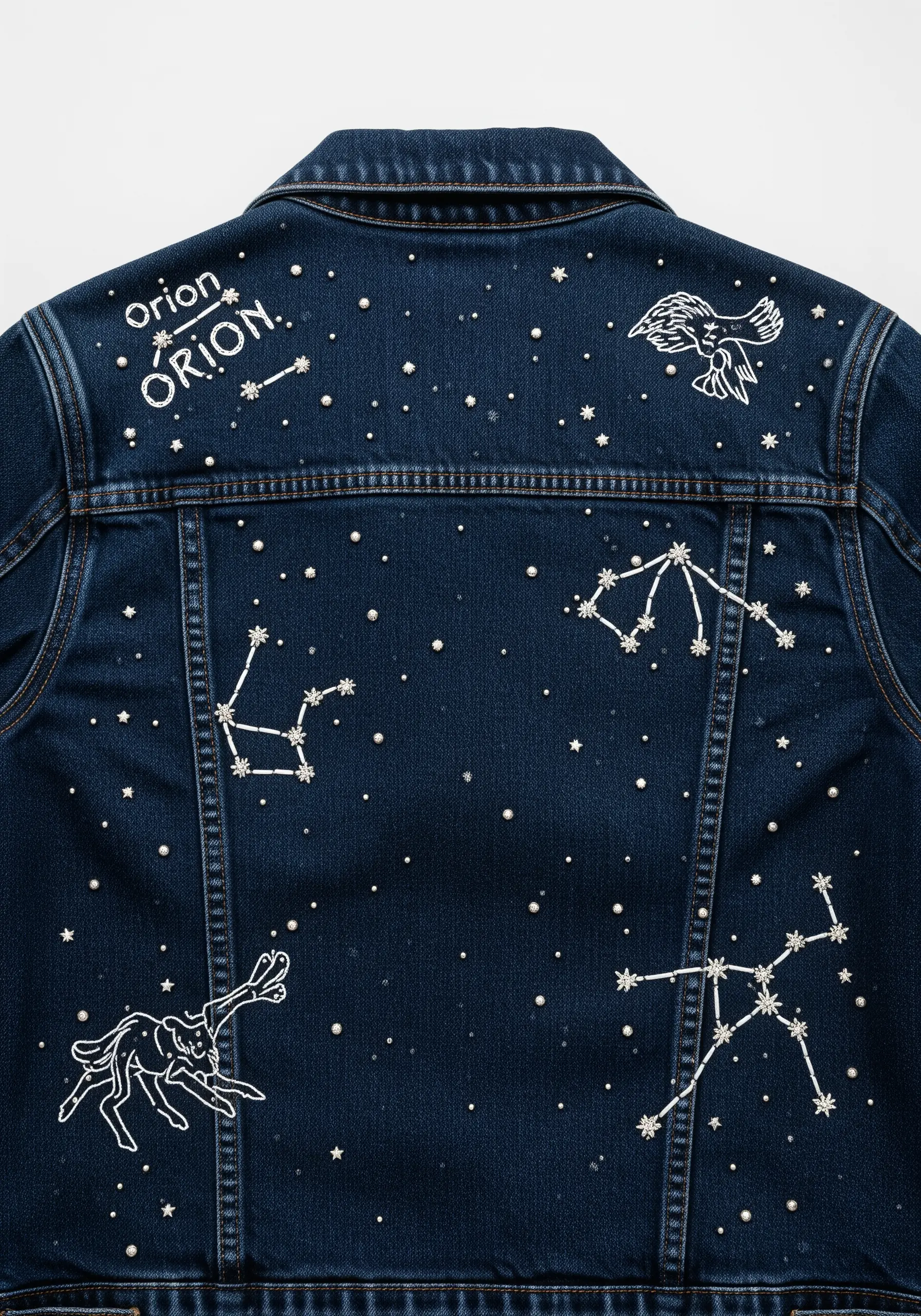 Minimalist constellations stitched in white thread and beads on the back of a dark blue denim jacket.