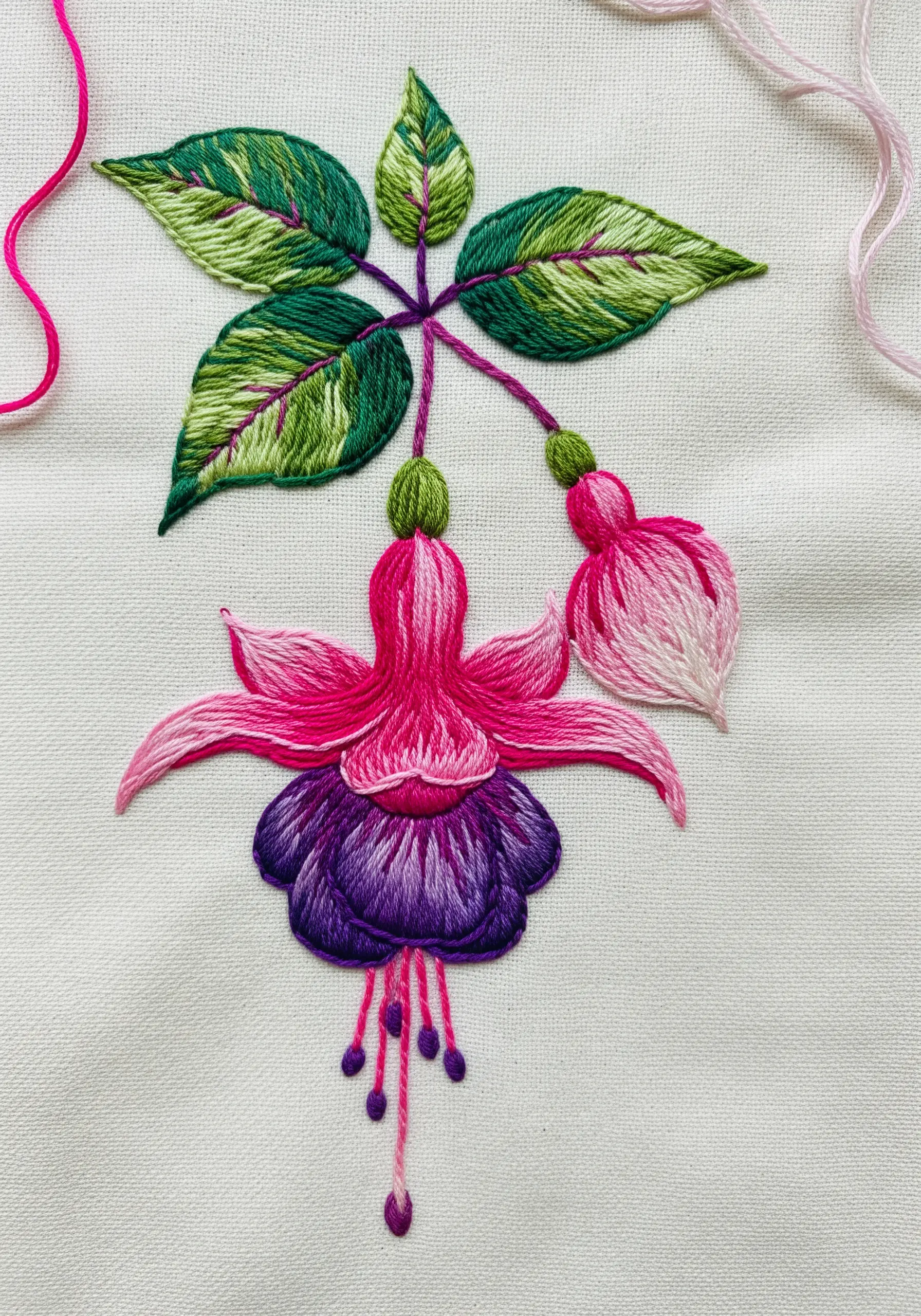 A fuchsia flower with a purple satin-stitched skirt and pink gradient petals.