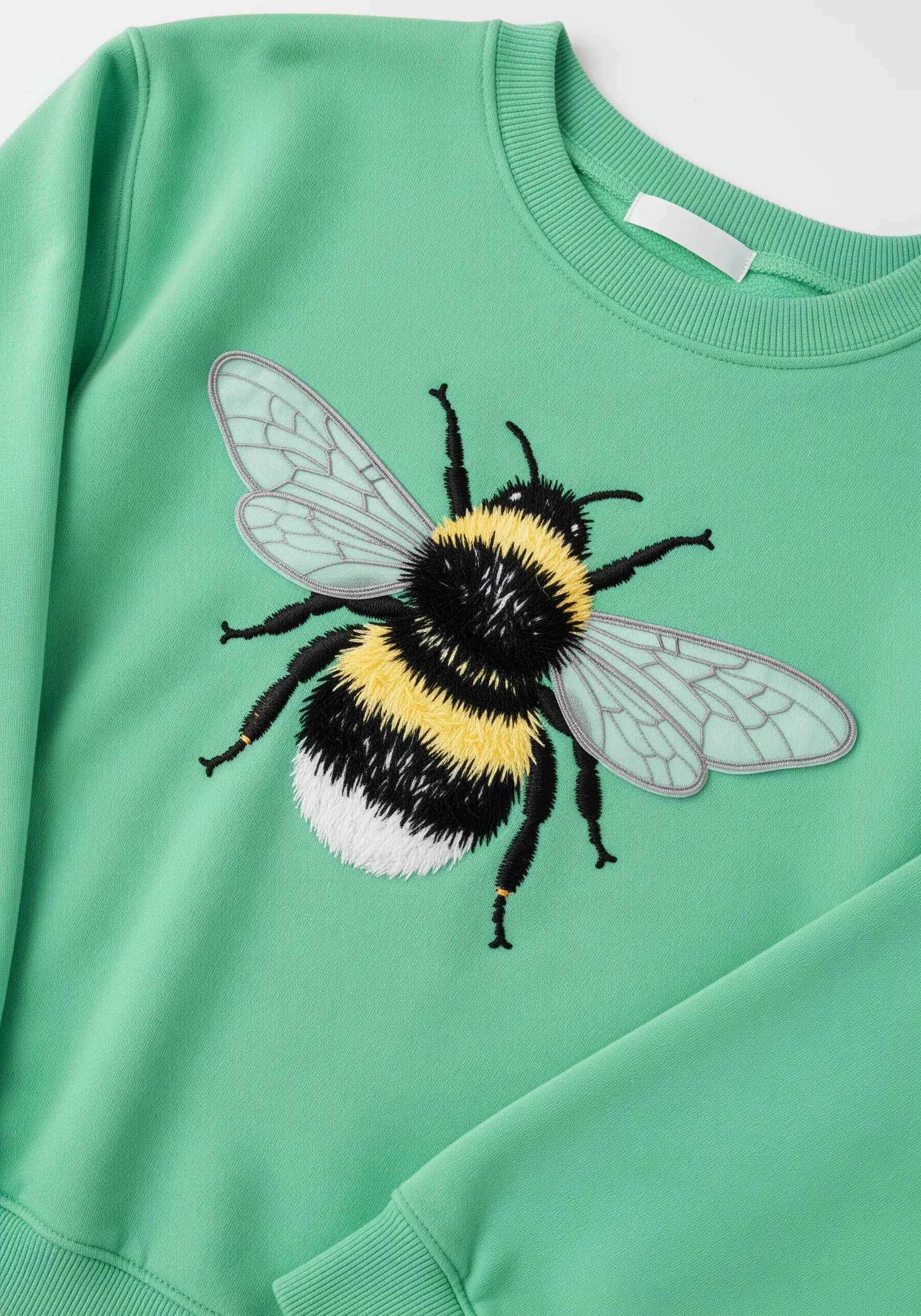 A large, realistically embroidered bumblebee on the front of a mint green sweatshirt.