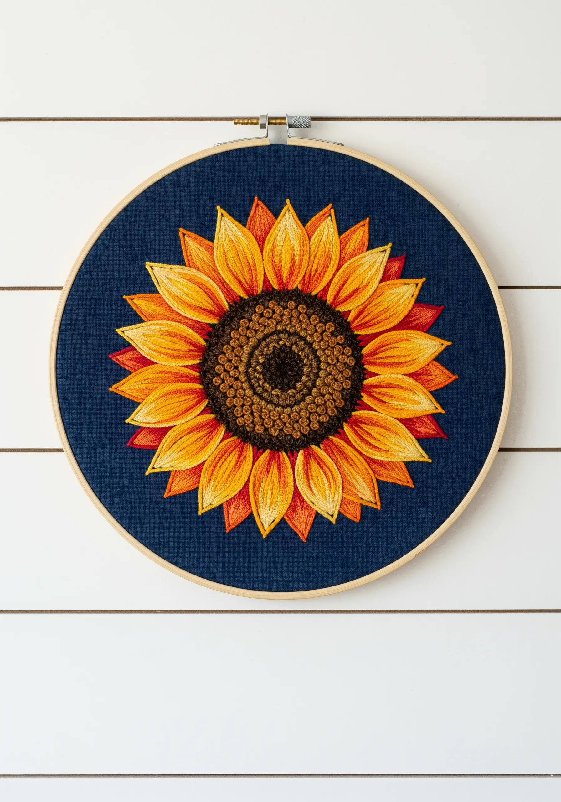 Detailed sunflower hoop art on navy fabric with realistic color blending and textured center.