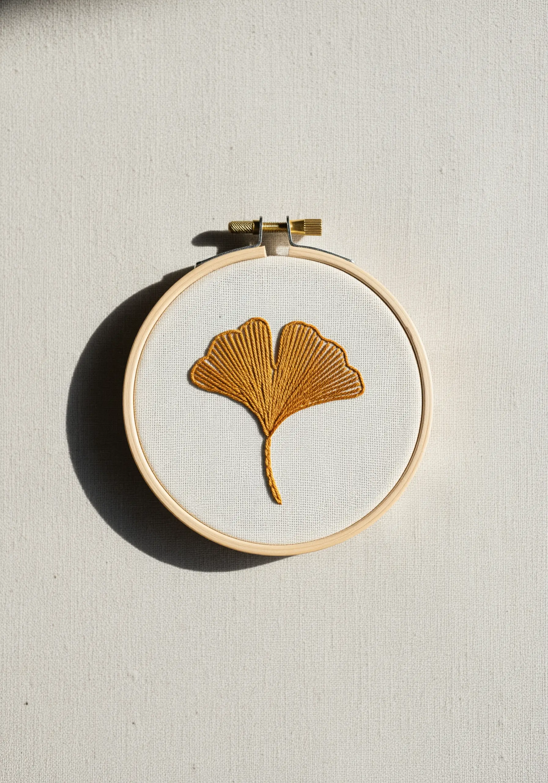 A single ginkgo leaf embroidered in mustard yellow using directional satin stitch.