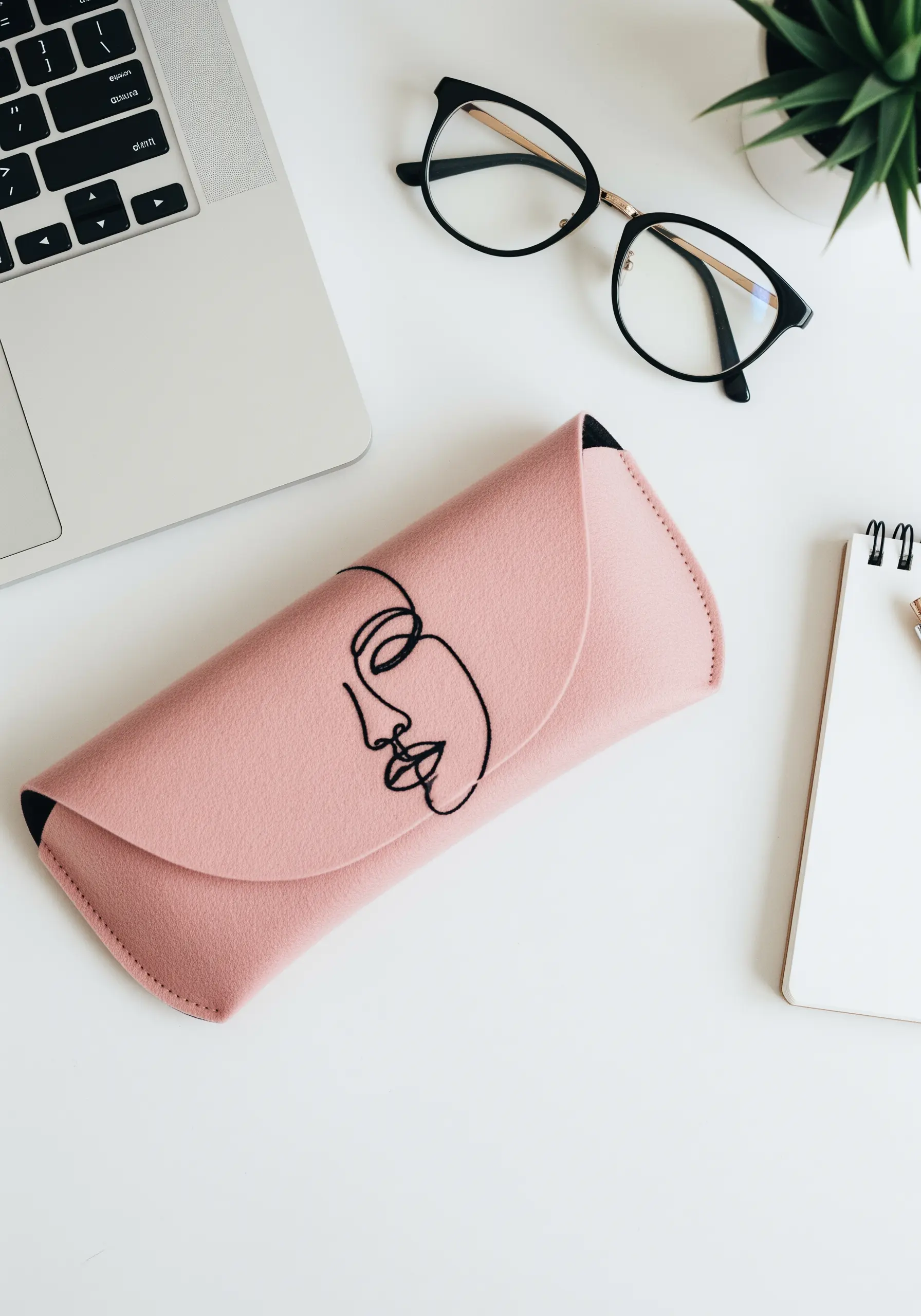 A minimalist single-line face embroidered in black thread on a pink felt glasses case