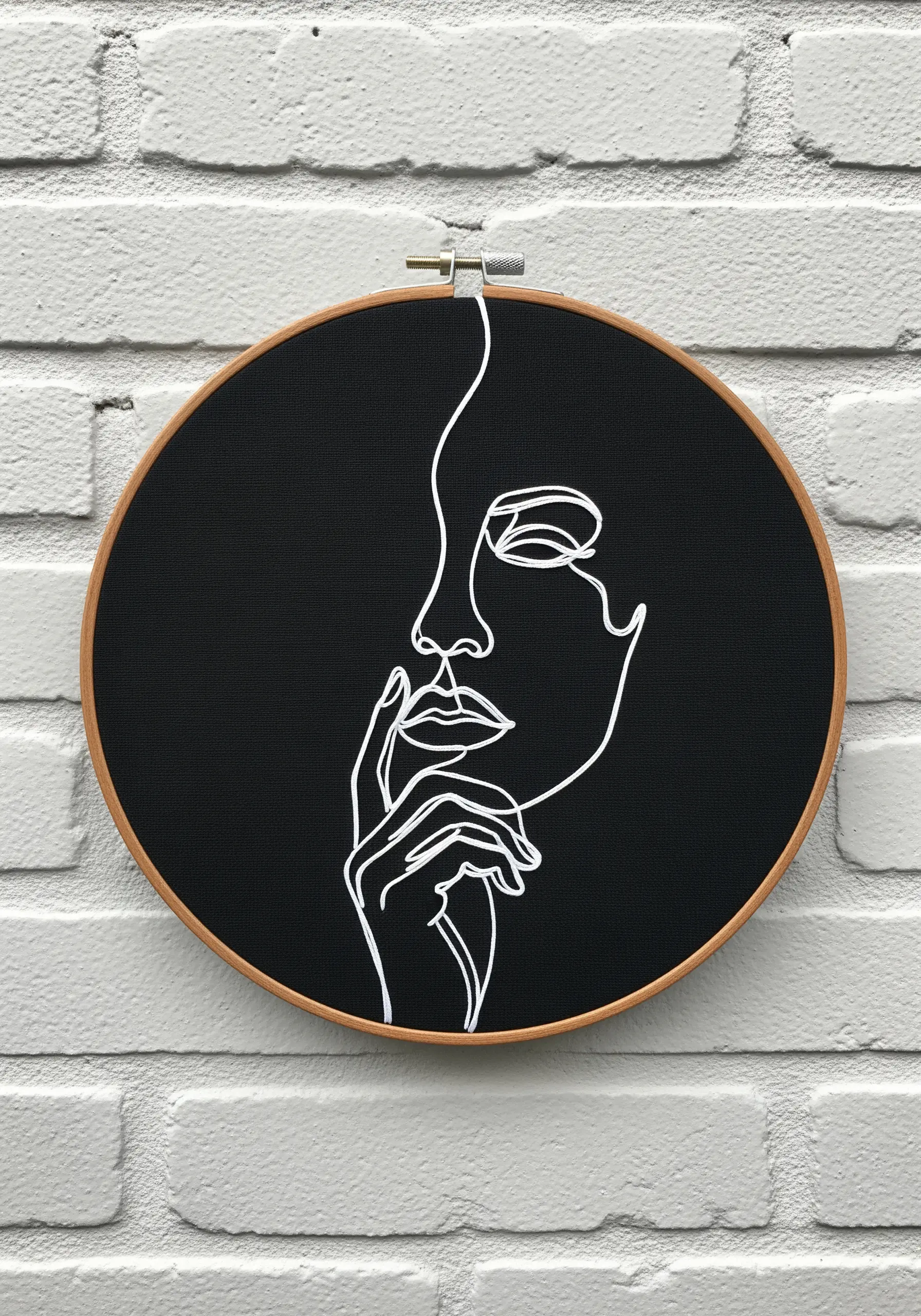Bright white thread creates a continuous line art portrait on a solid black fabric background.