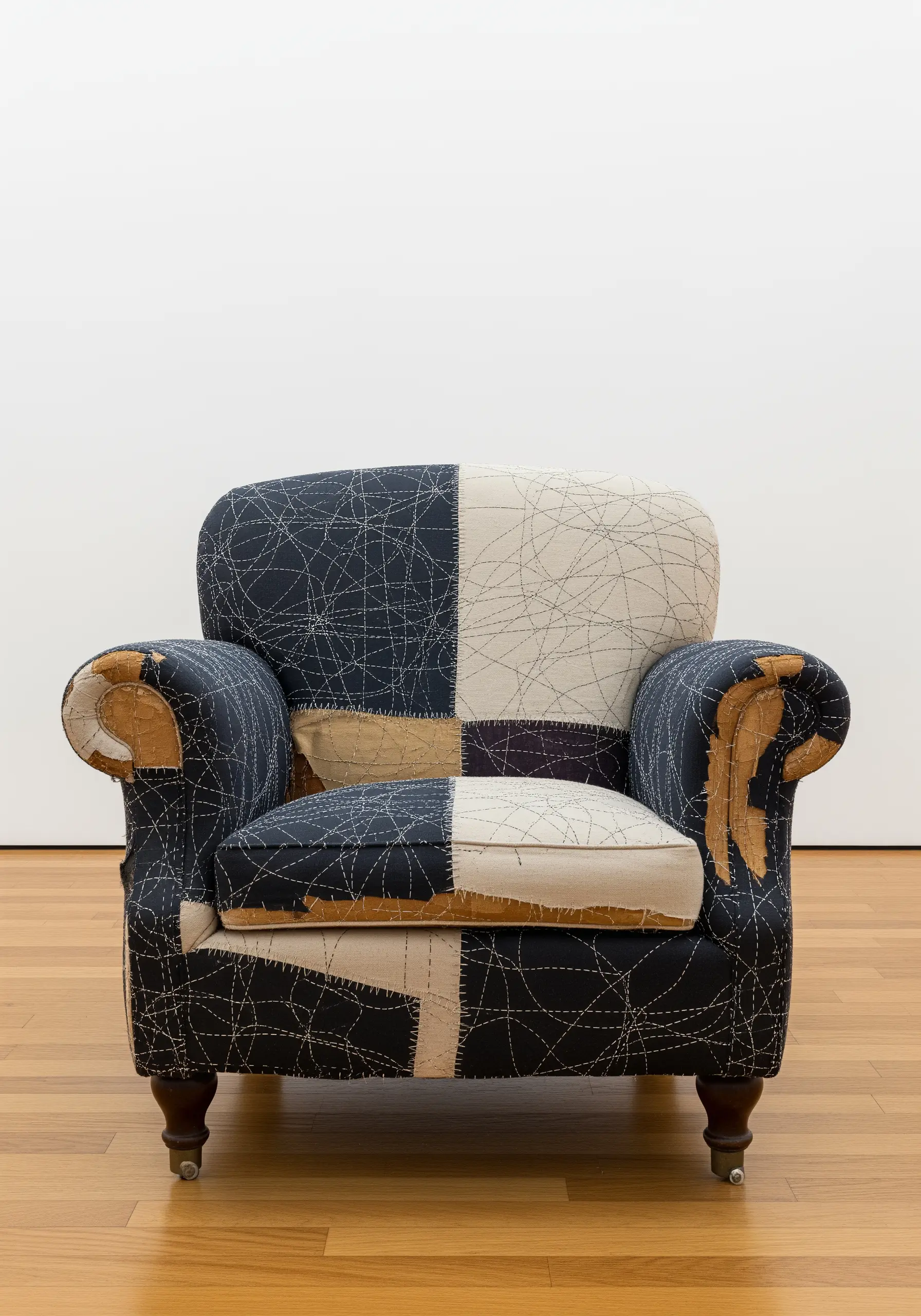 A patchwork armchair with visible, decorative running stitches in white thread on dark fabric.