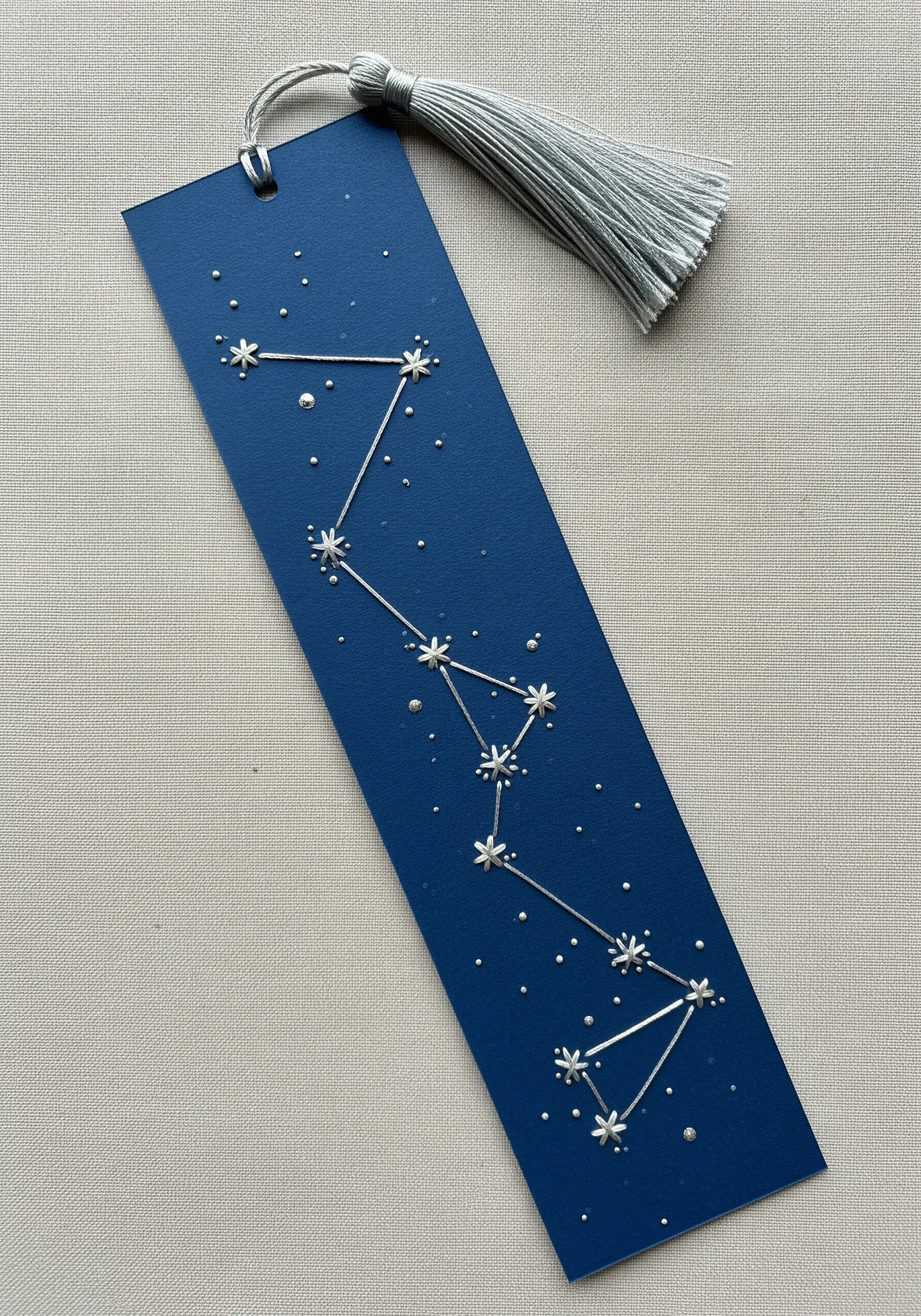 Embroidered constellation on a dark blue bookmark with silver metallic details