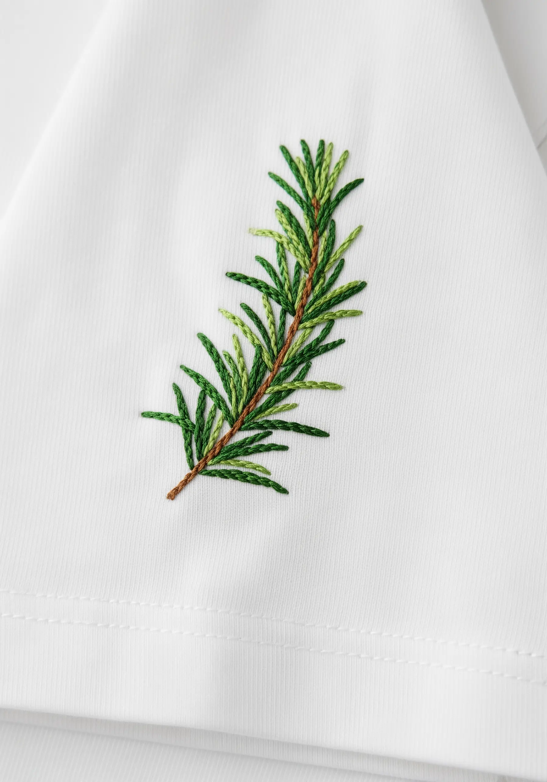 A sprig of rosemary embroidered in multiple shades of green.
