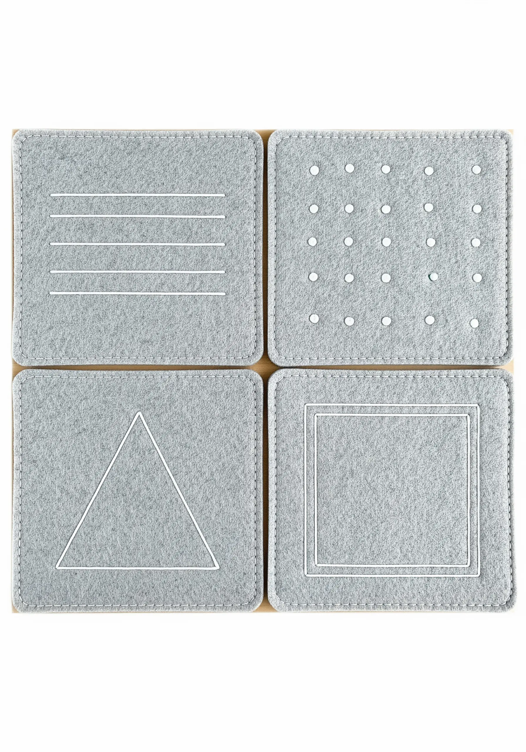 Four grey felt coasters, each embroidered with a simple white geometric pattern.