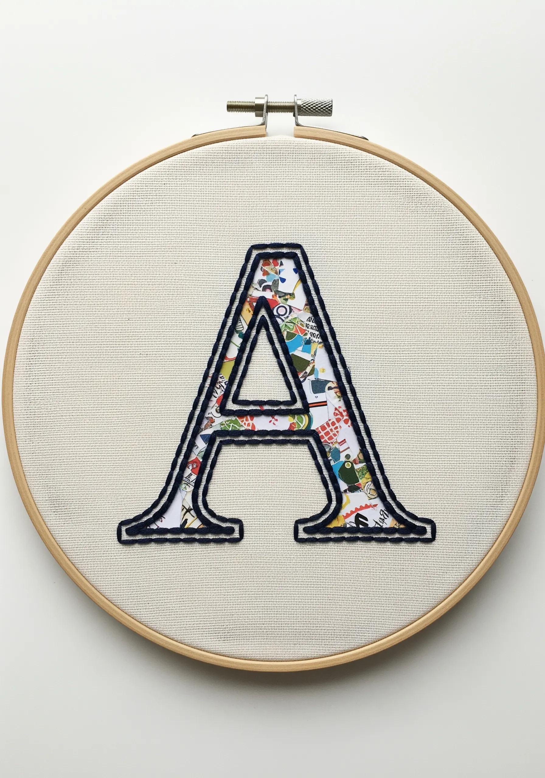 A large letter 'A' appliqué filled with colorful map-patterned fabric and outlined in dark thread