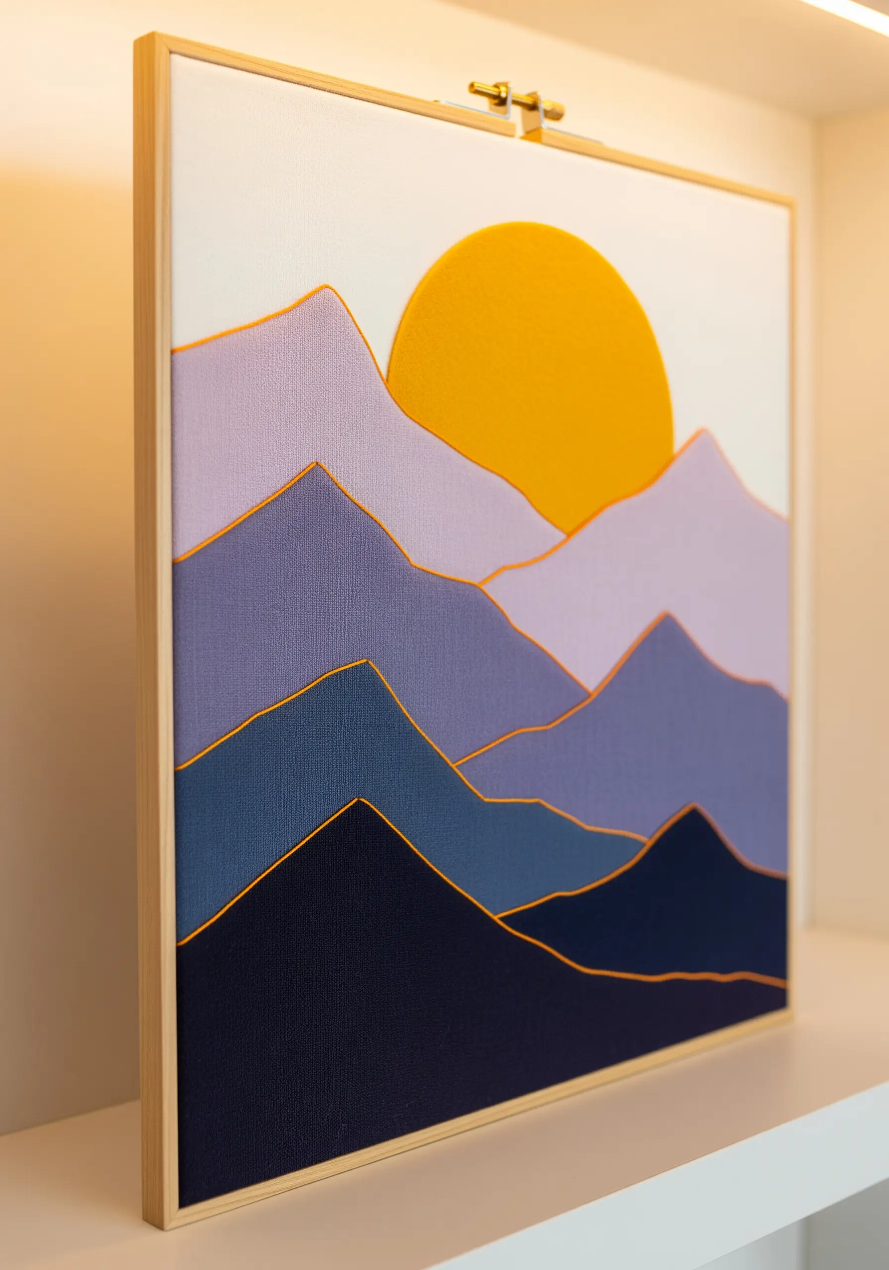 A layered fabric collage of a mountain landscape with golden thread couched along the edges.