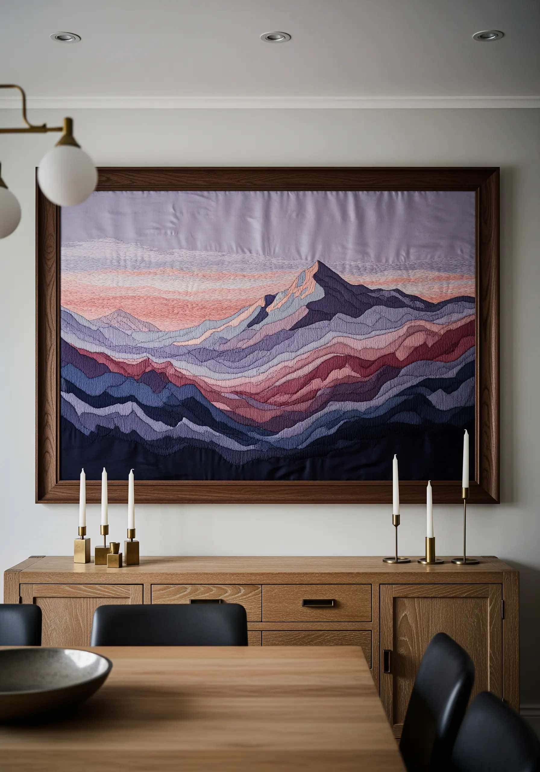 A large framed embroidery of a mountain landscape with colorful contoured lines.