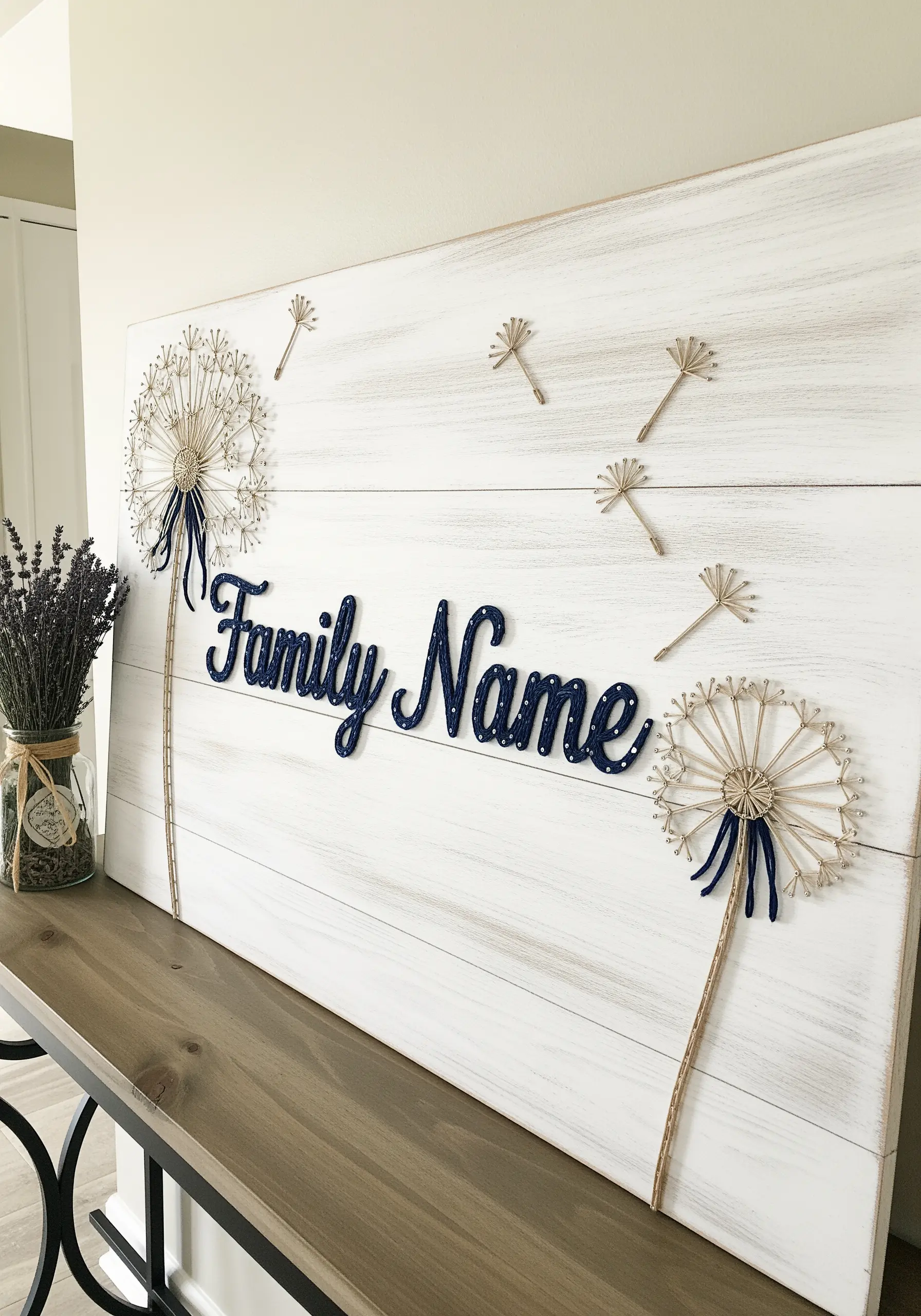 A personalized family name sign with 3D navy lettering flanked by delicate string art dandelions.