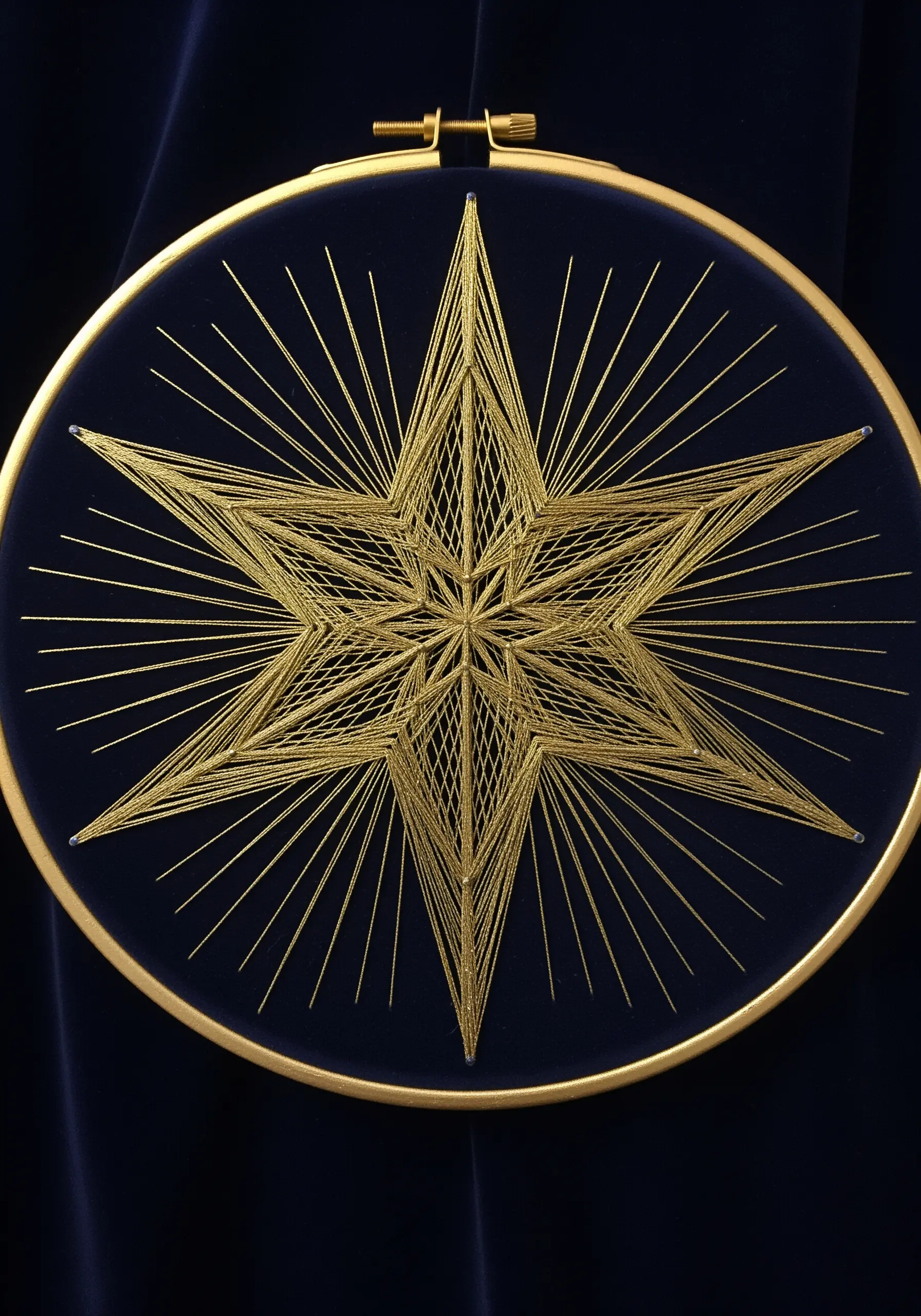 Geometric gold metallic string art star on a dark blue velvet background.