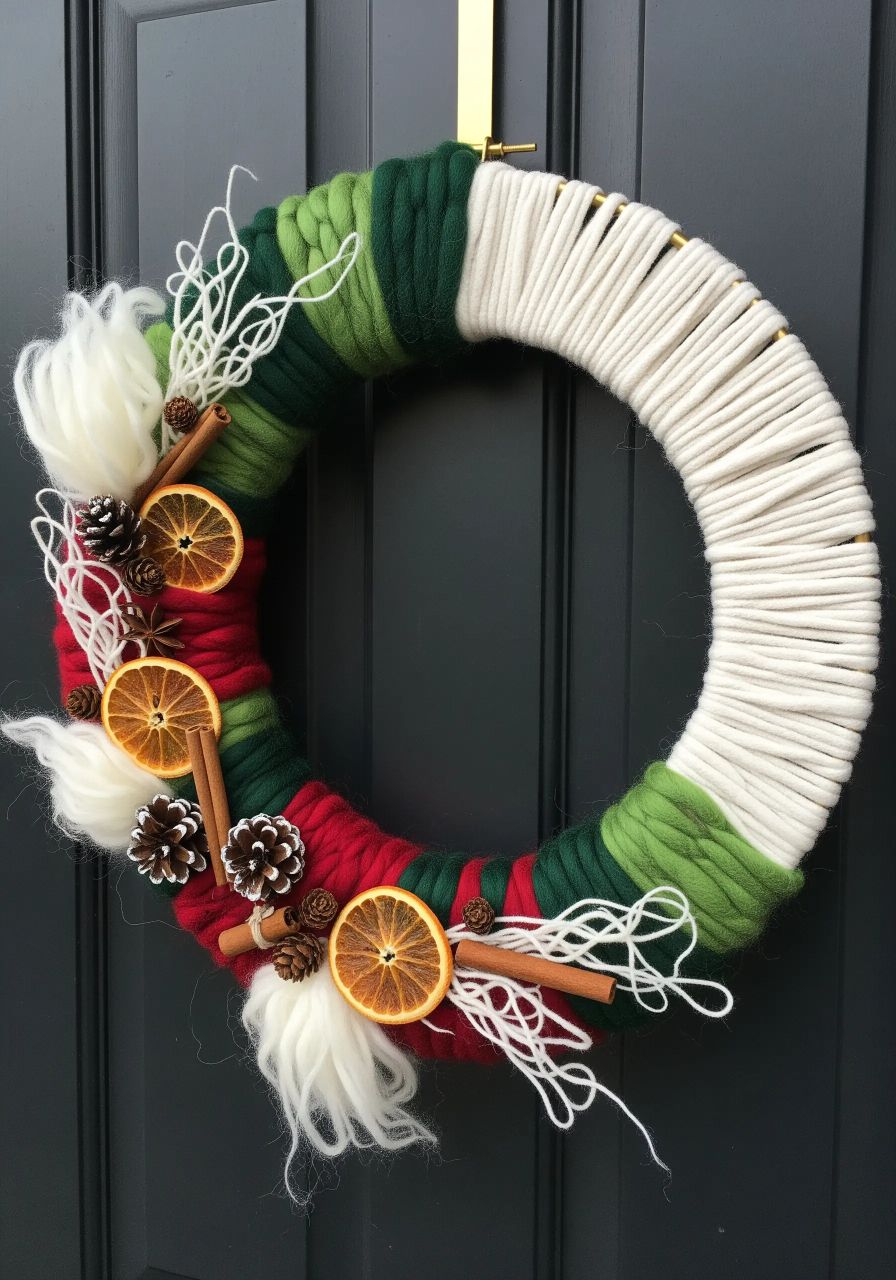 Yarn-wrapped winter wreath with color blocks of red, green, and white, adorned with dried oranges.
