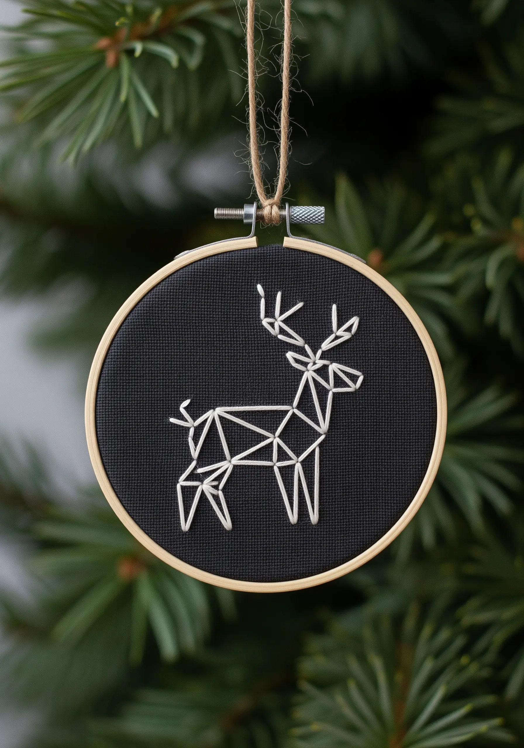 Geometric reindeer ornament embroidered with white thread on black Aida cloth.