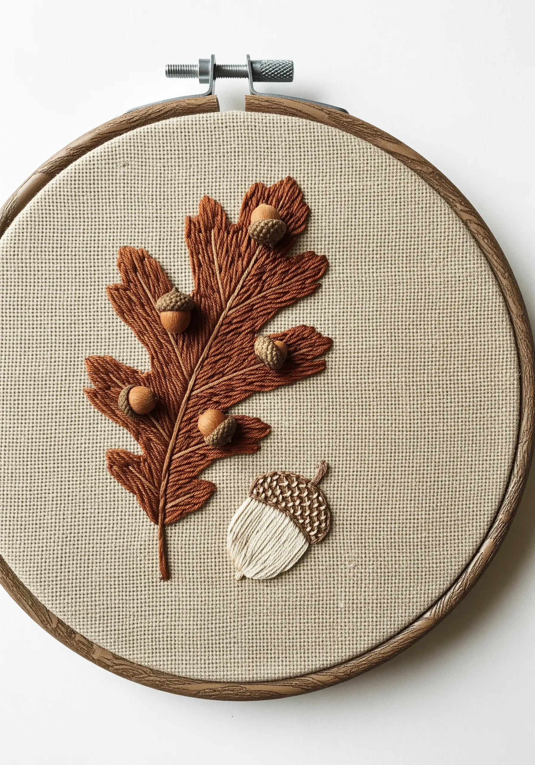 An oak leaf and acorns embroidered with different stitches to create realistic textures.