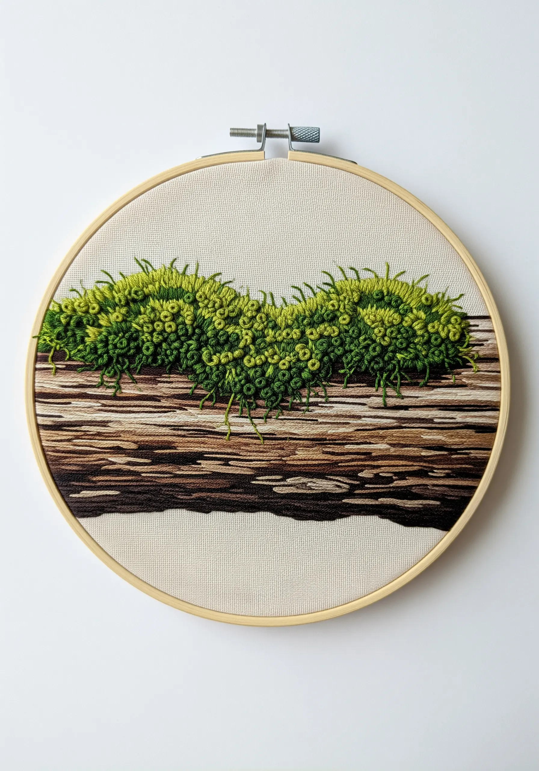 Embroidery of moss on a log, with loose threads creating a trailing effect.
