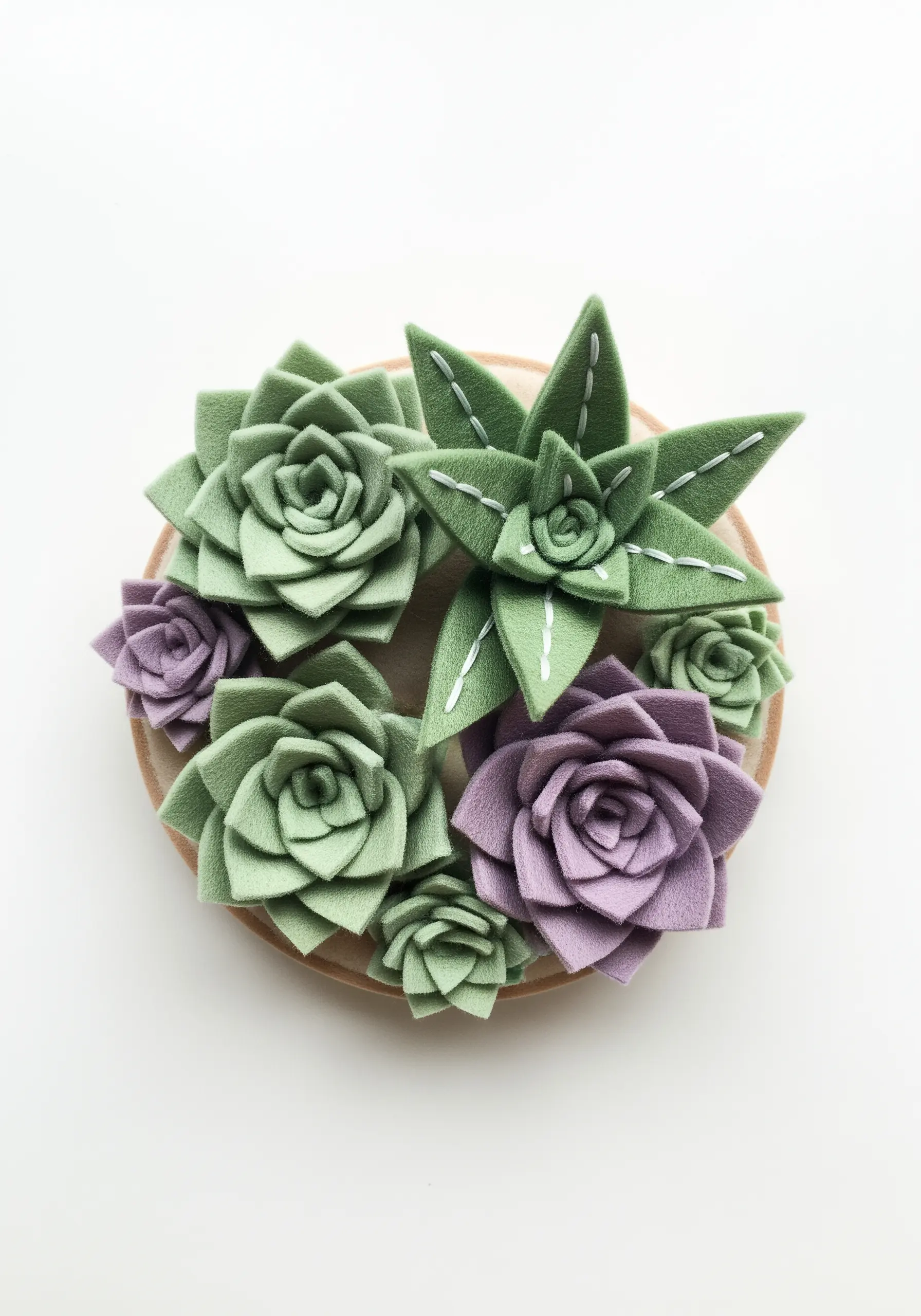 Three-dimensional succulents made from green and purple felt arranged in a hoop.