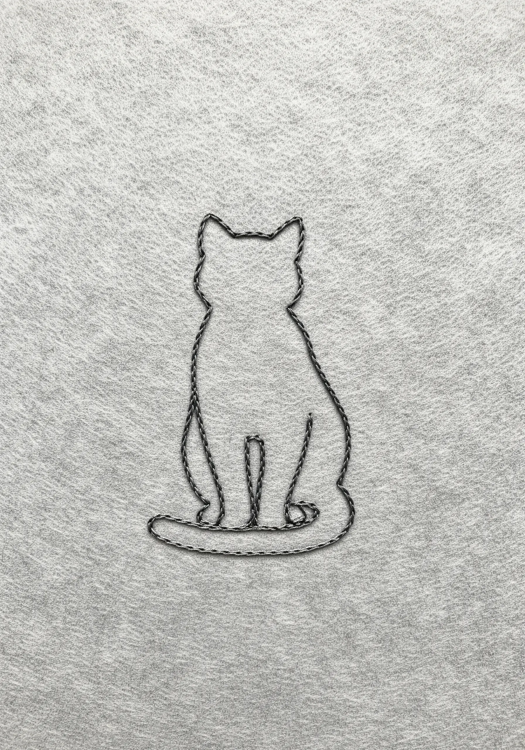 The outline of a sitting cat embroidered with a raised, cord-like whipped backstitch.
