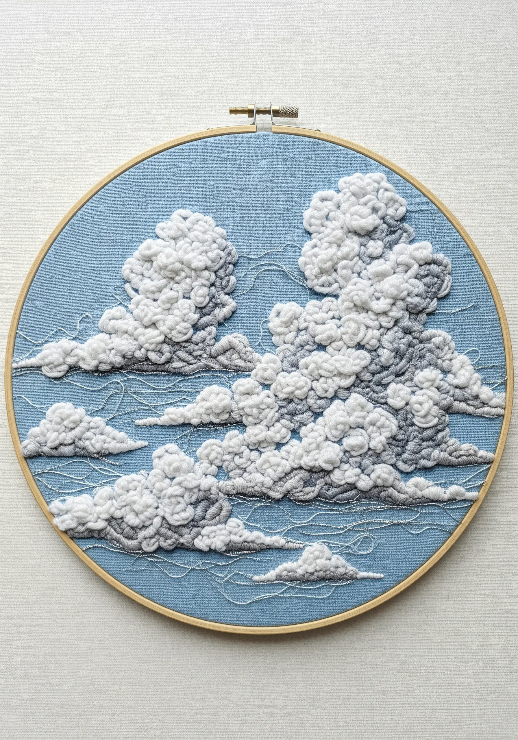 Highly textured cloud embroidery in a hoop using white and grey French knots.