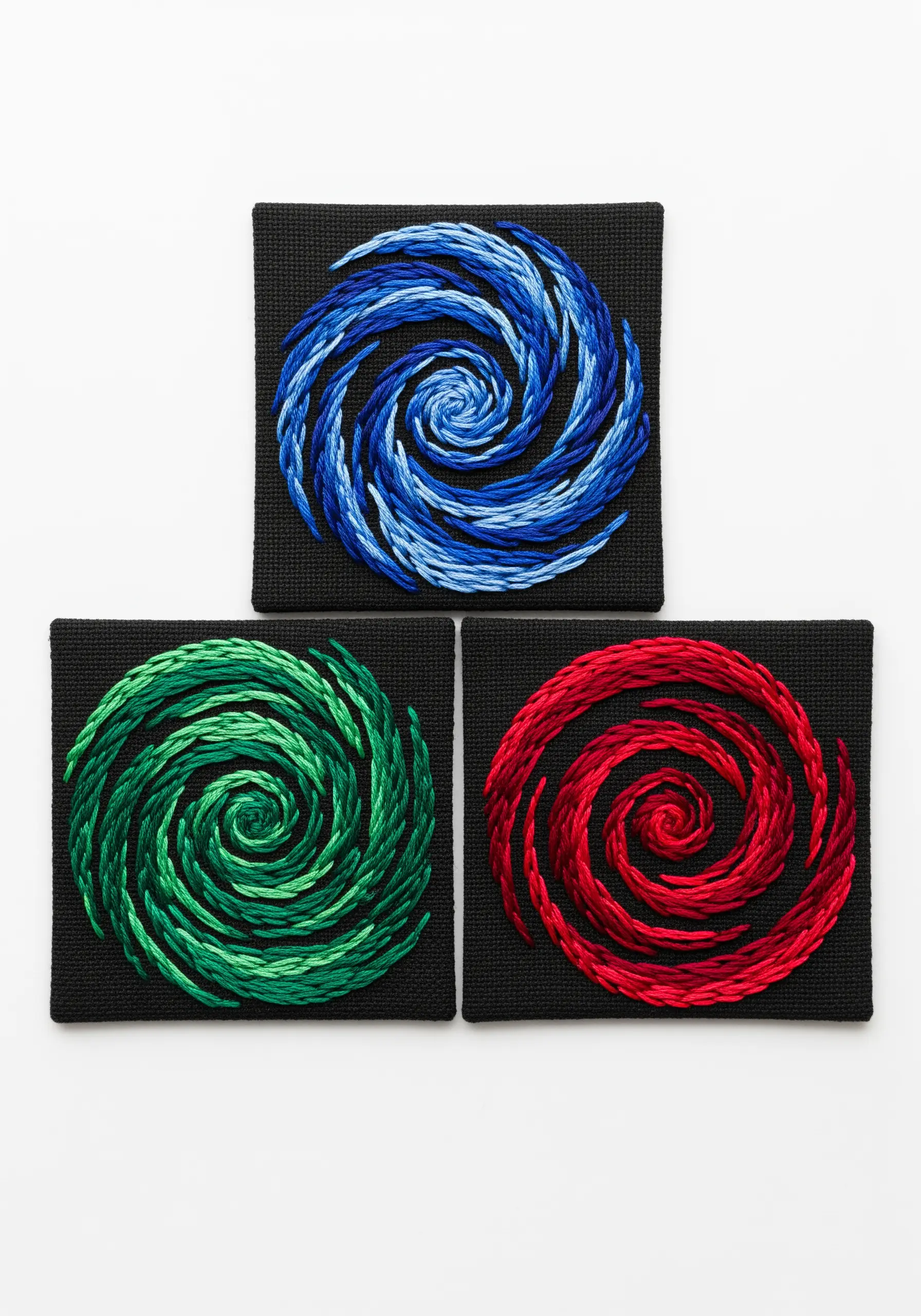 Three embroidered spirals in blue, green, and red color gradients on black canvas.