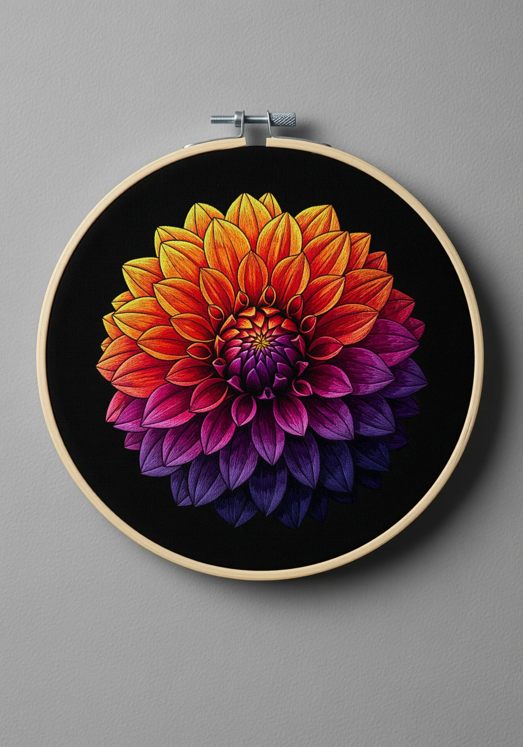 Vibrant dahlia embroidered with a sunset gradient of yellow, orange, and purple on black fabric.