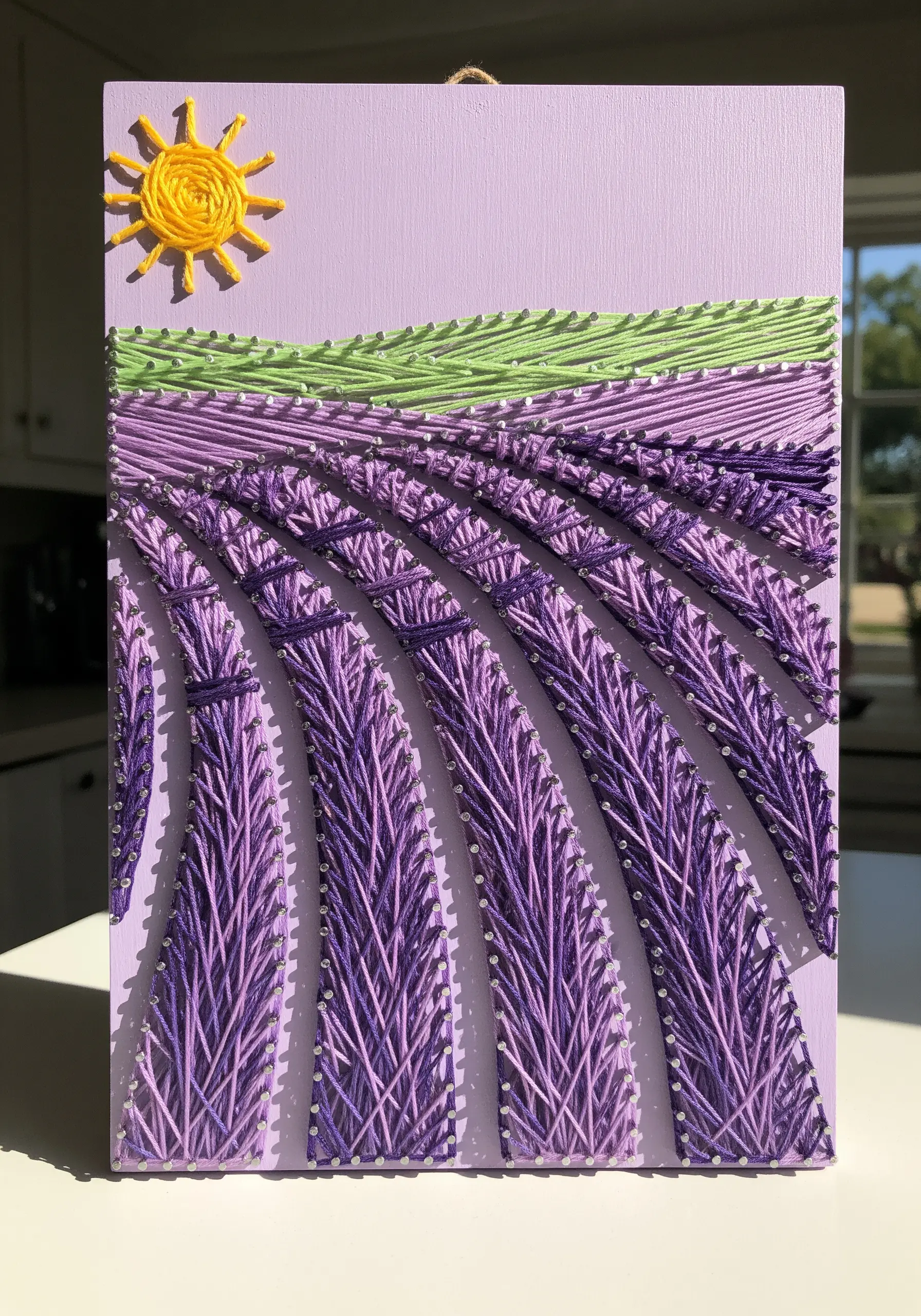 String art of a lavender field with angled purple stitches creating rows and perspective.