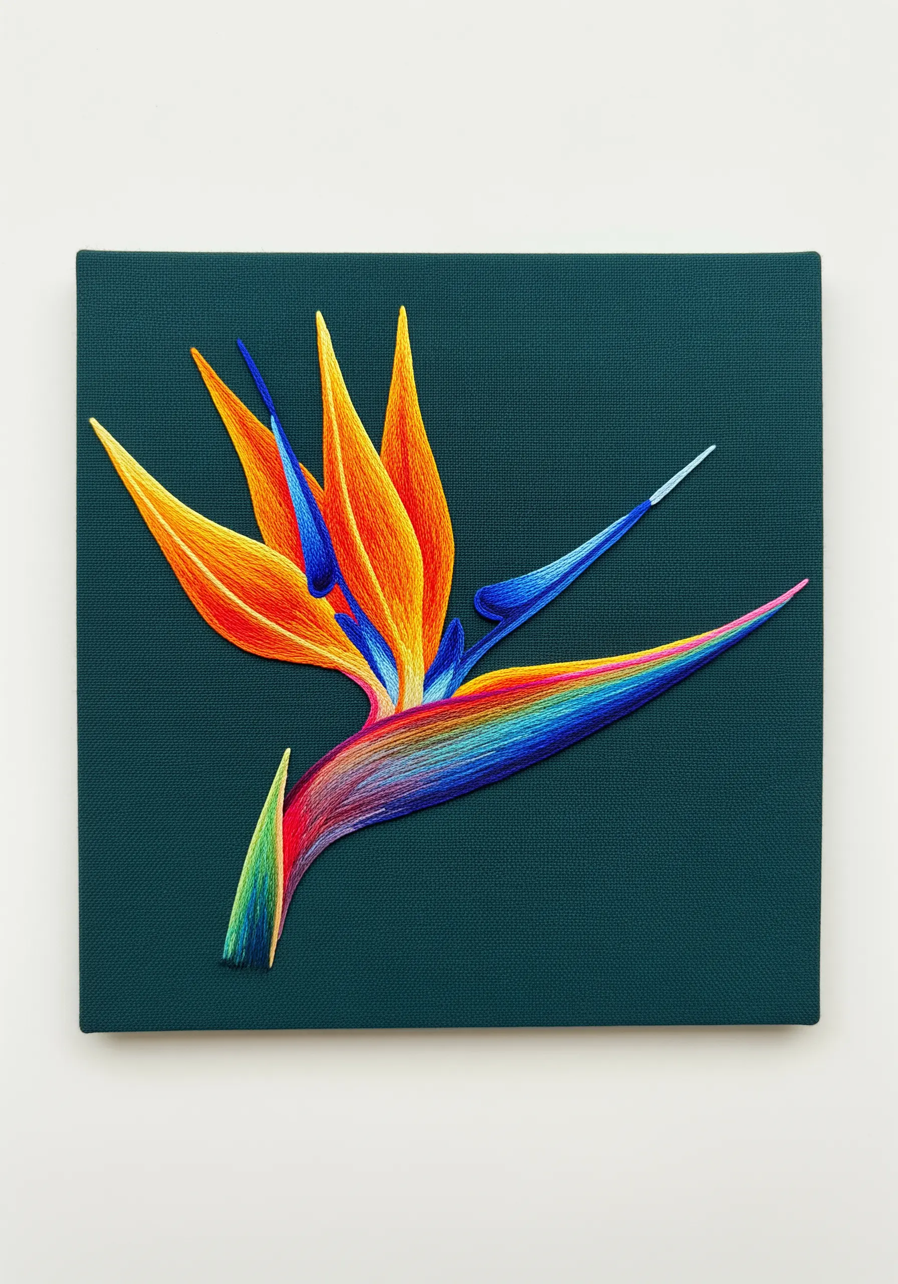 A bird of paradise flower with a vibrant rainbow gradient, stitched on dark canvas.