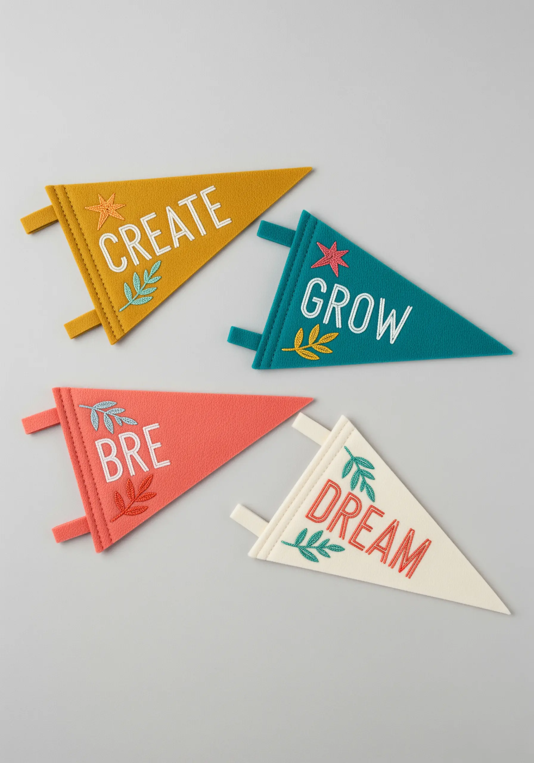 Four colorful felt pennants with embroidered words like 'Create,' 'Grow,' and 'Dream.'