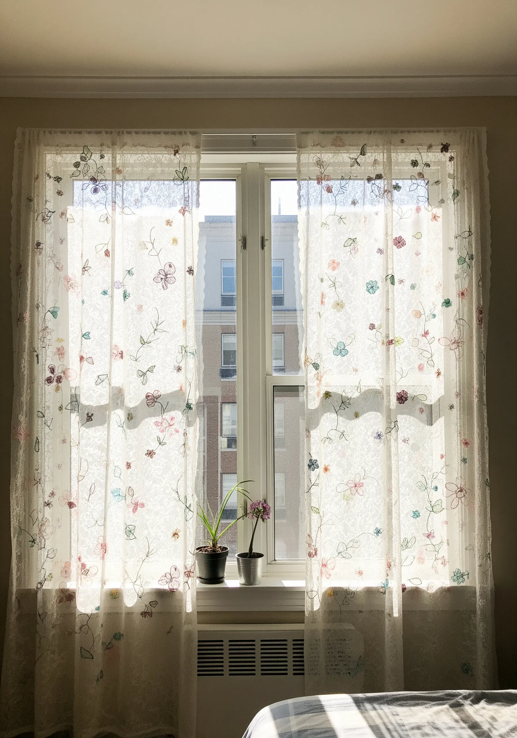 Sheer lace curtains with small, colorful embroidered flowers scattered across the fabric.