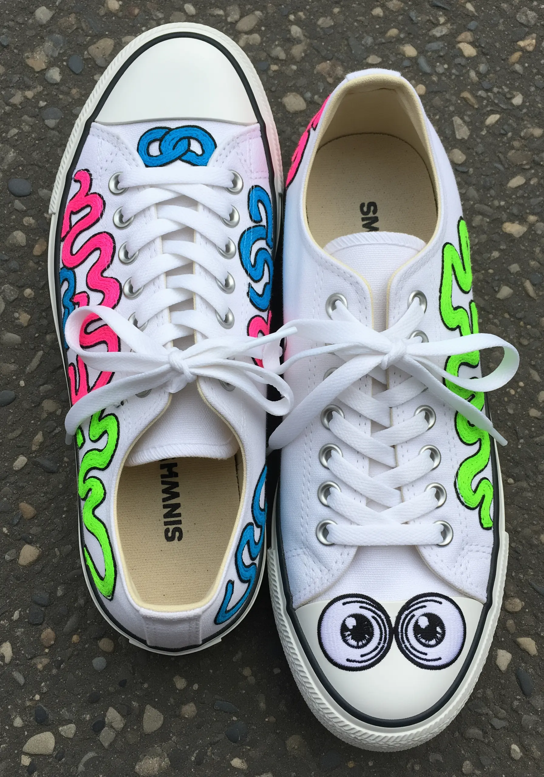 White canvas sneakers with neon pink, blue, and green graffiti-style embroidery and cartoon eyes