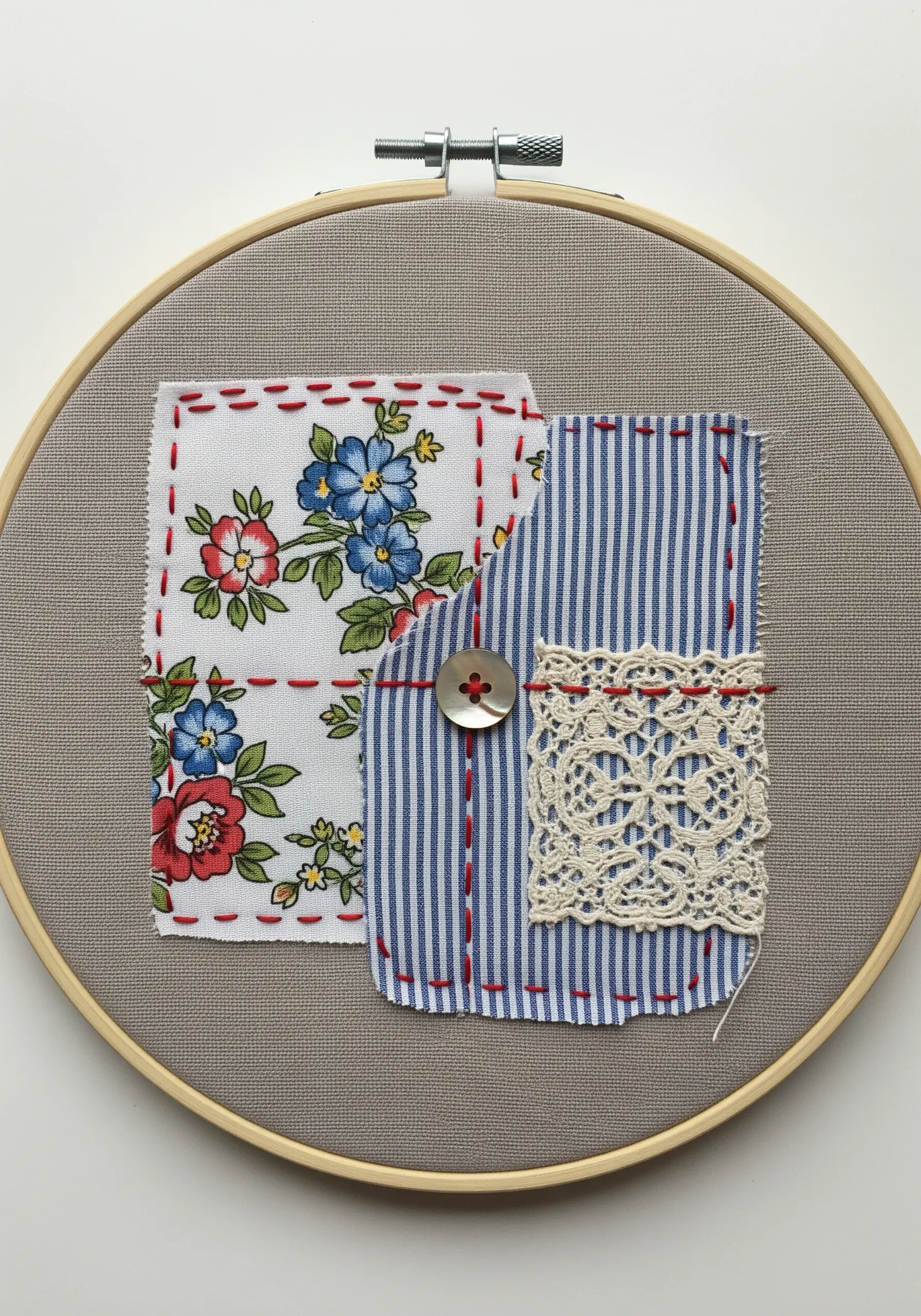 Two fabric scraps, floral and striped, joined by a button and decorative running stitches.
