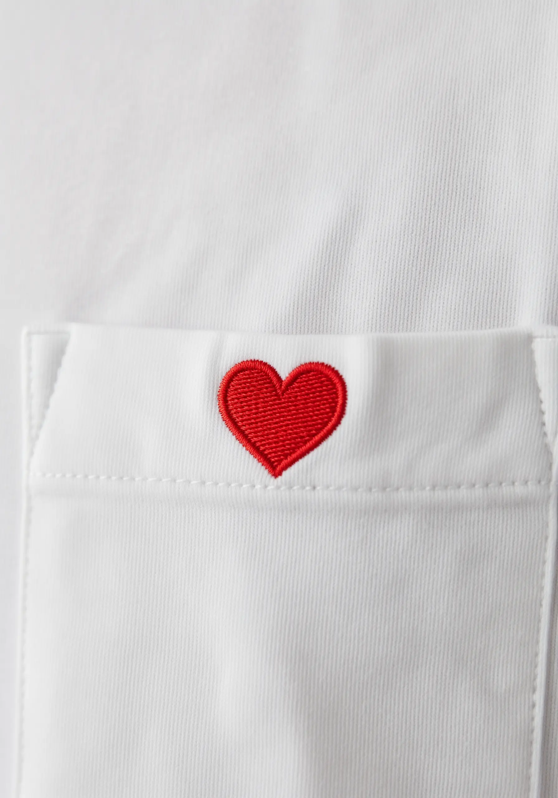 A perfectly smooth, red satin-stitched heart on the pocket of a white shirt.