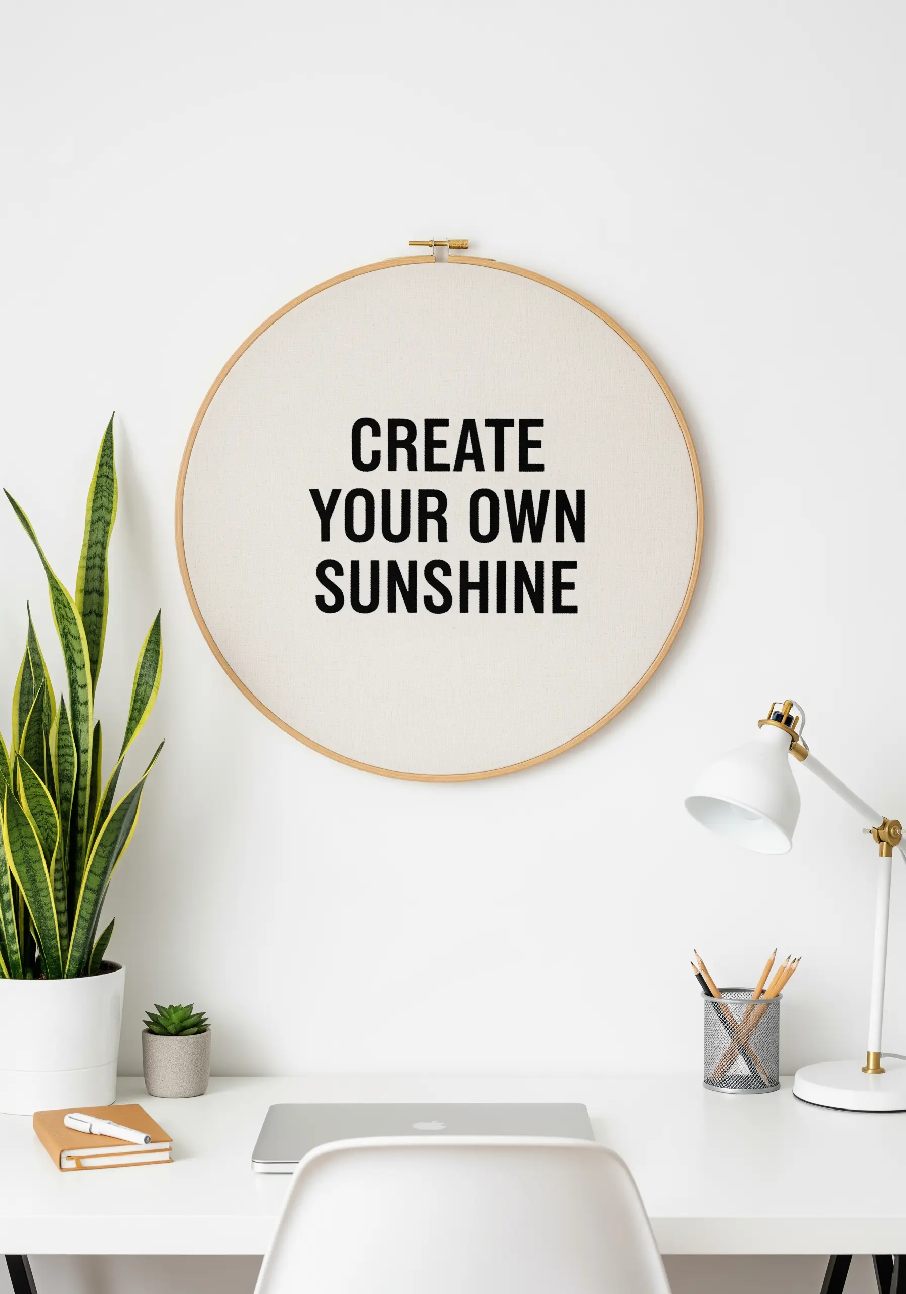 Bold black embroidered sans-serif quote in a large wooden hoop.