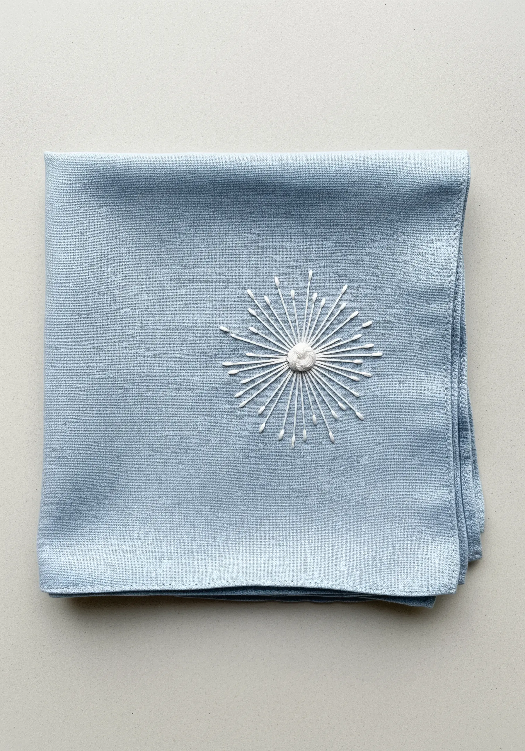 A white starburst motif made of straight stitches and French knots.