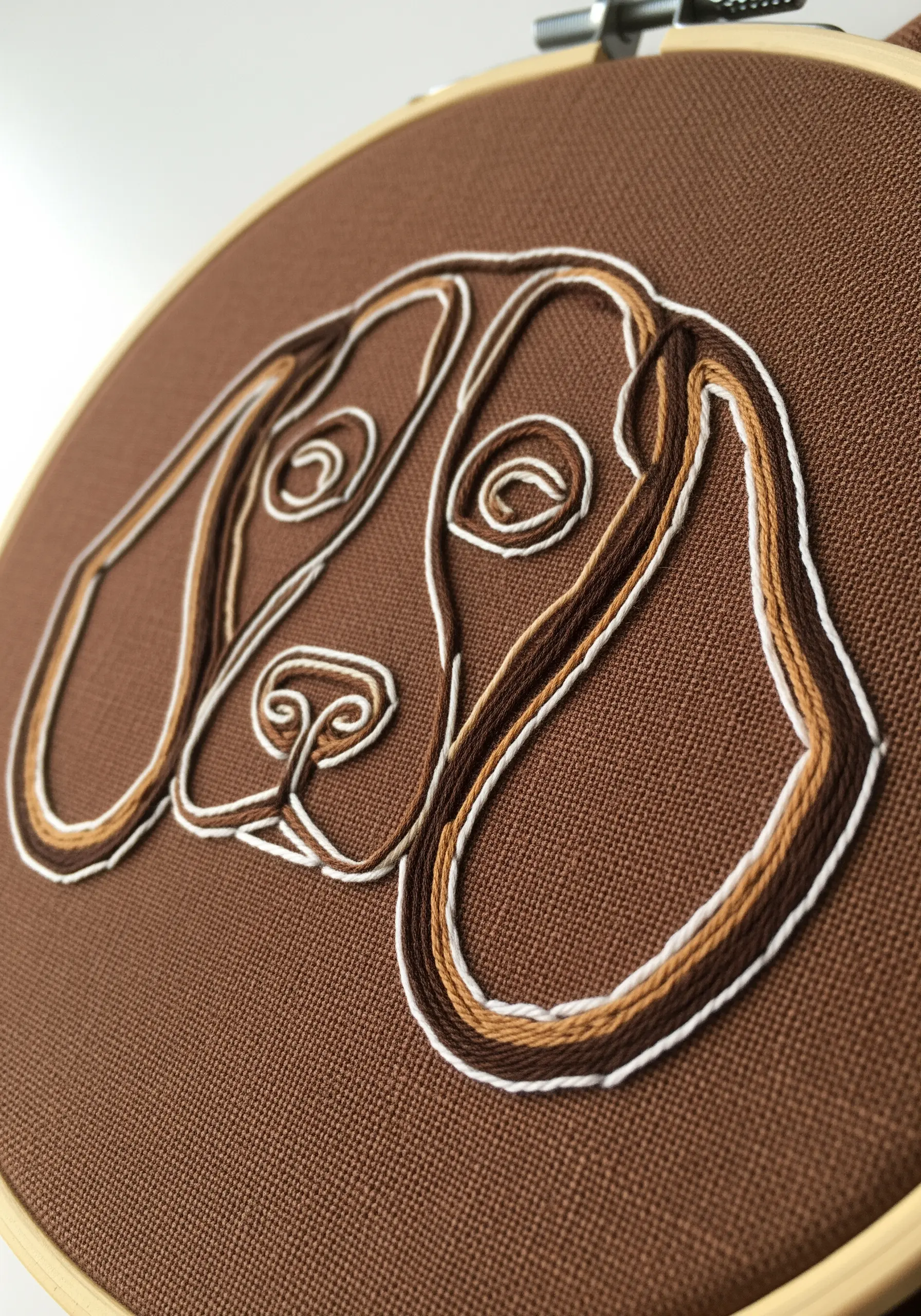 Close-up of a hound dog outline stitched with three different colors of thread.