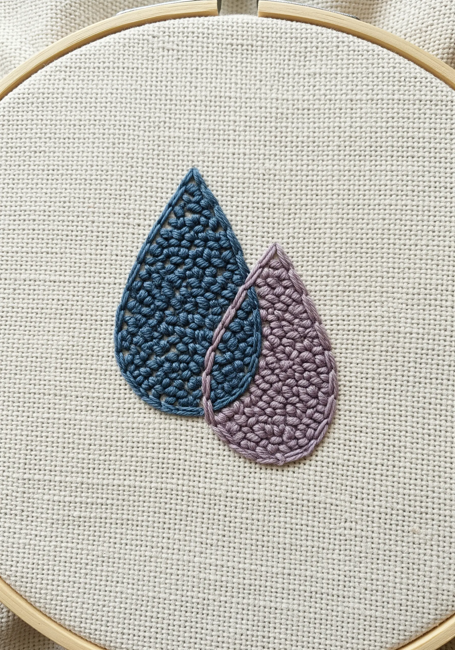 Two teardrop shapes filled with a dense, woven stitch in blue and purple.