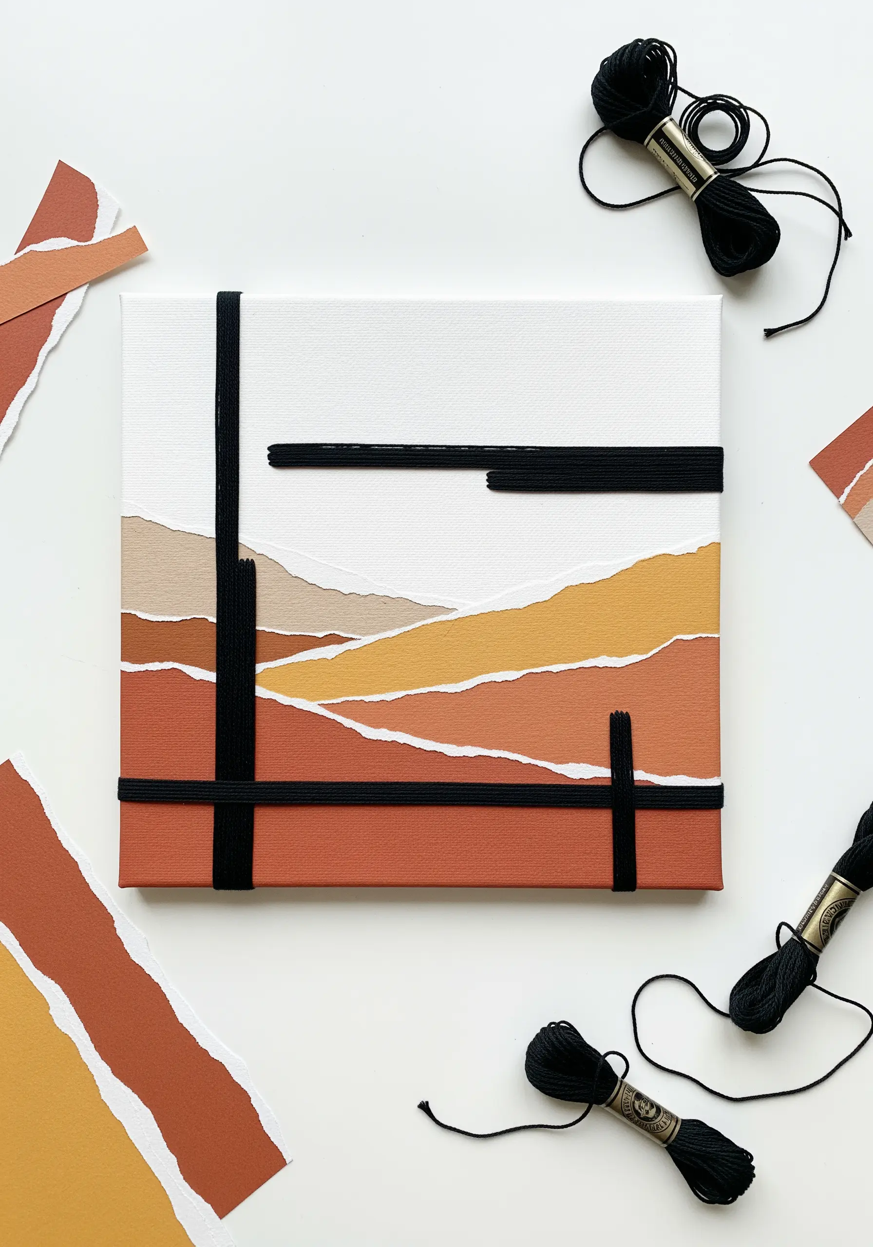 Abstract landscape made from torn paper collage on canvas with bold black thread wrapped around it.