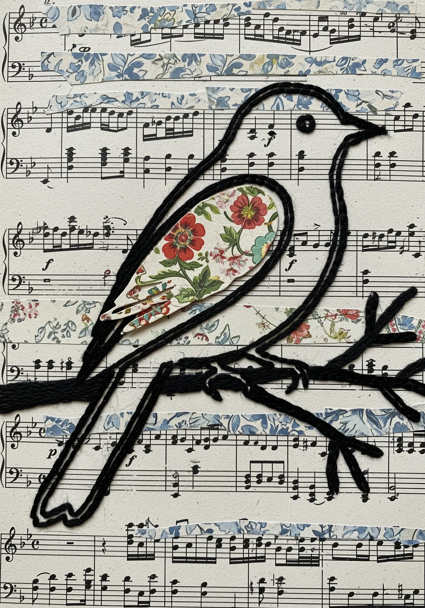 A bird outlined in black thread on a background of collaged sheet music and washi tape