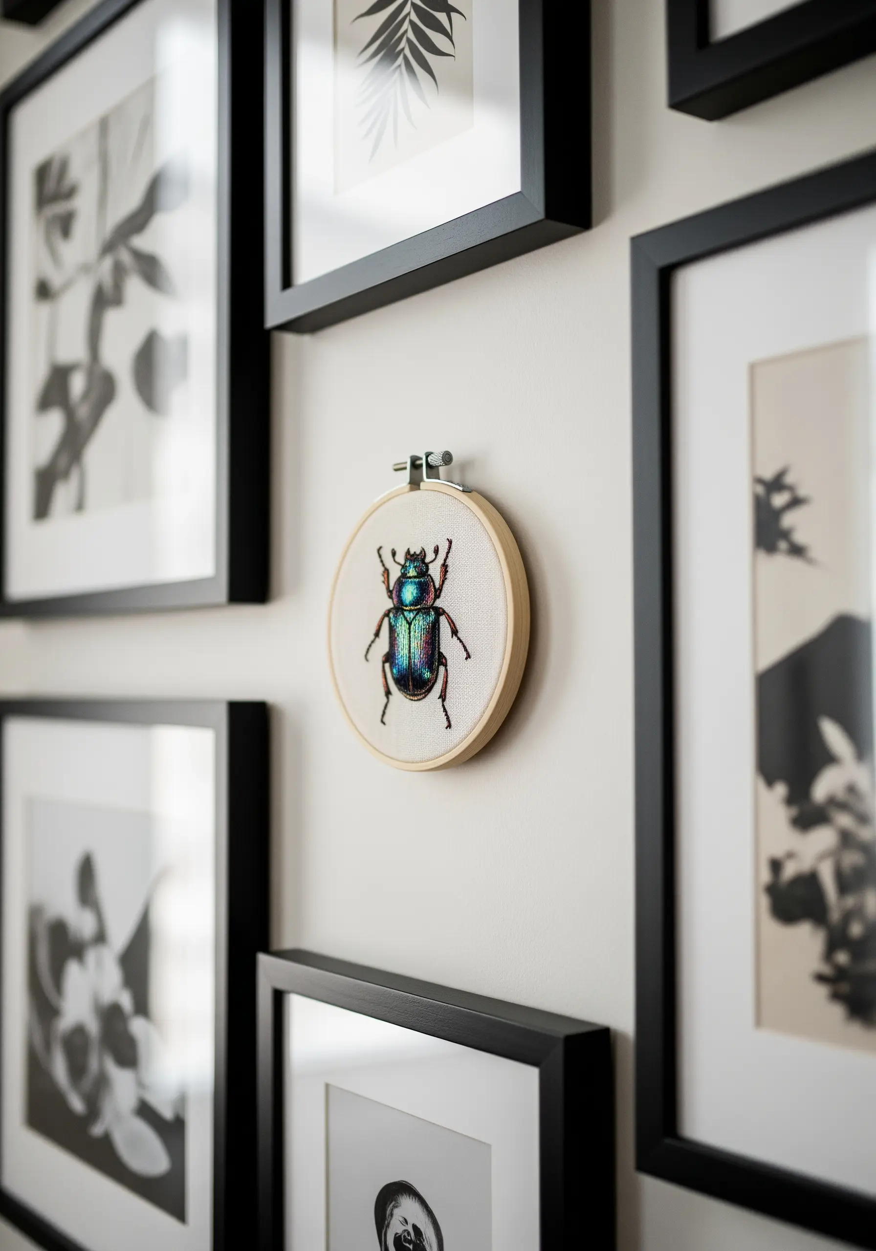 A realistic, iridescent beetle embroidered in a small hoop, part of a gallery wall.