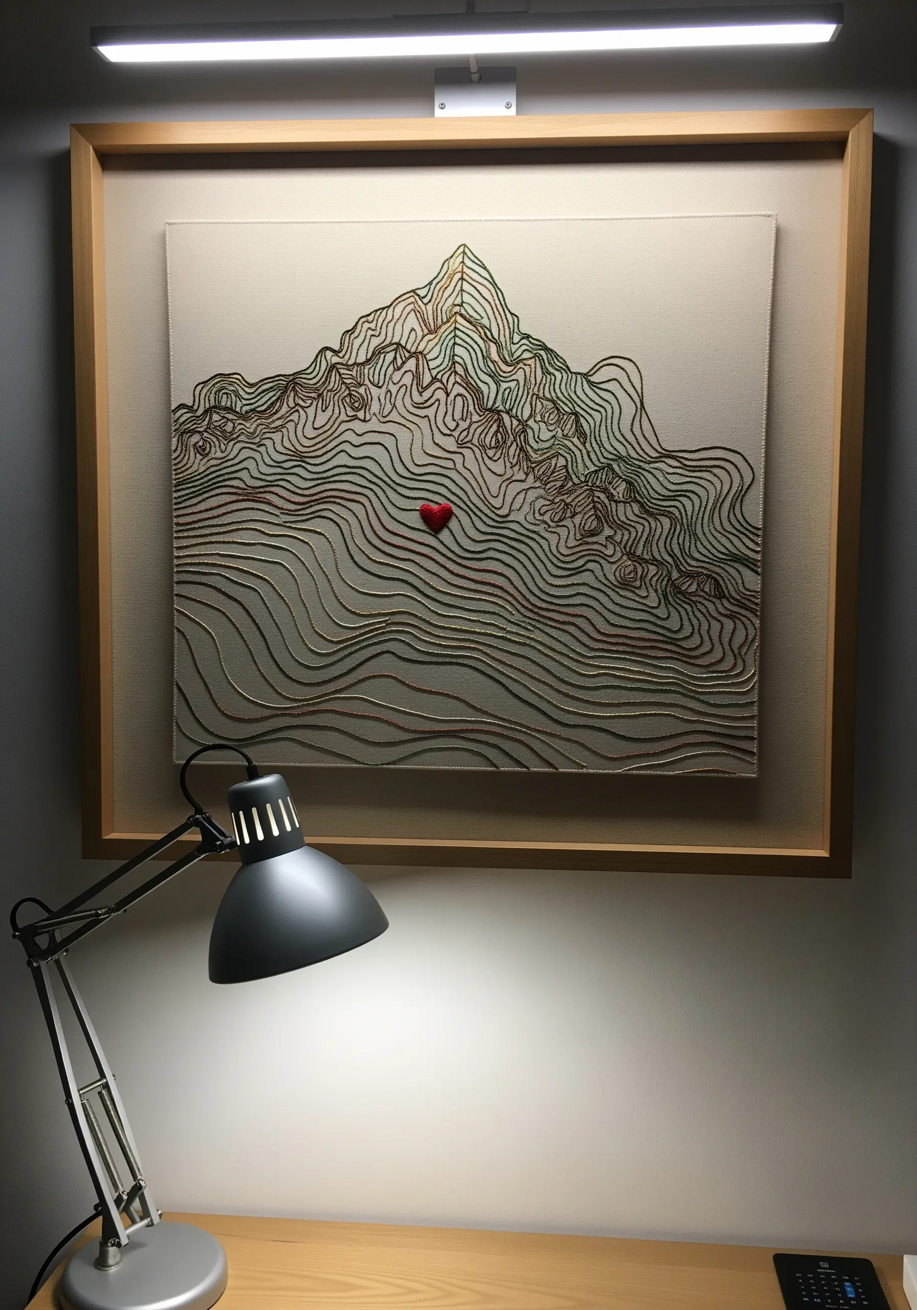 A topographical map embroidered with contour lines and a single small red heart.