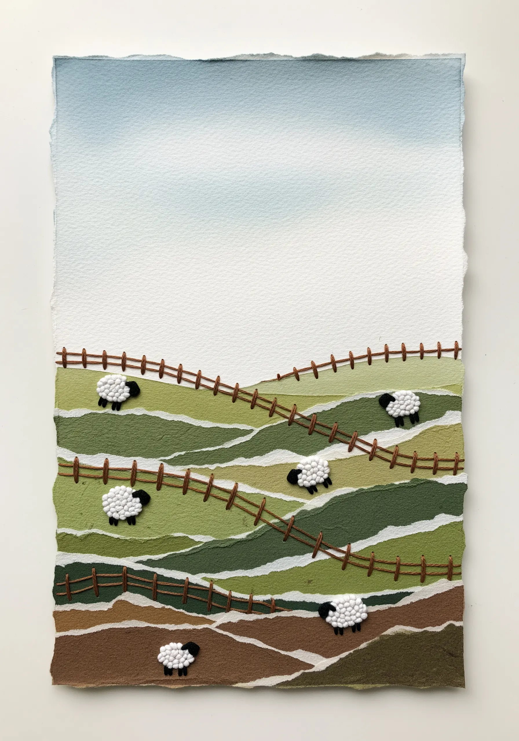 A landscape collage made from torn paper layers with embroidered fences and tiny sheep